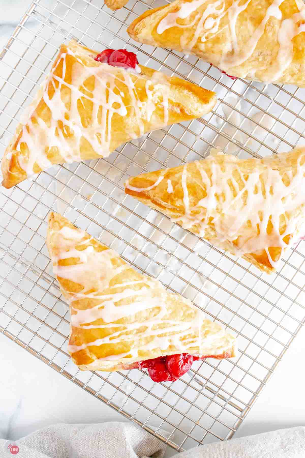wire rack topped with cherry turnovers with a vanilla glaze