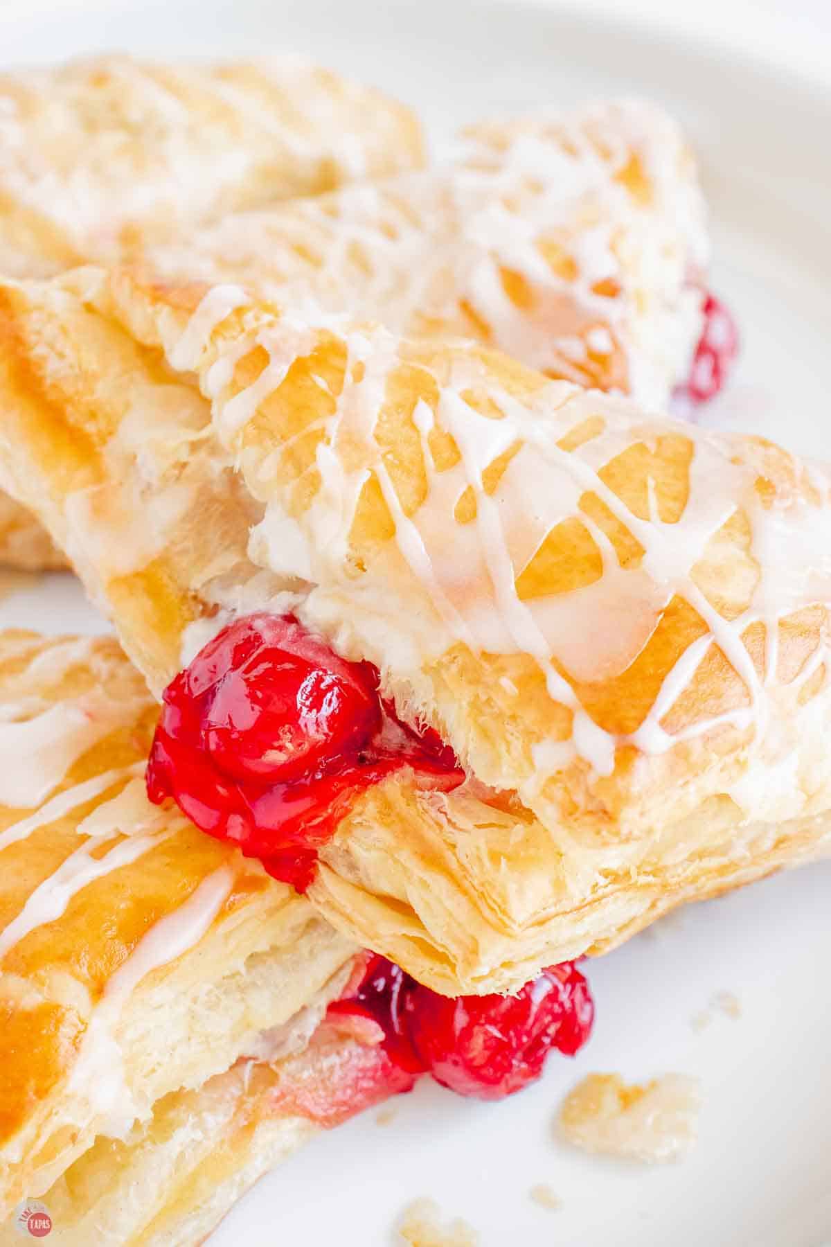 close up of puff pastry cherry turnover with vanilla glaze drizzled on top