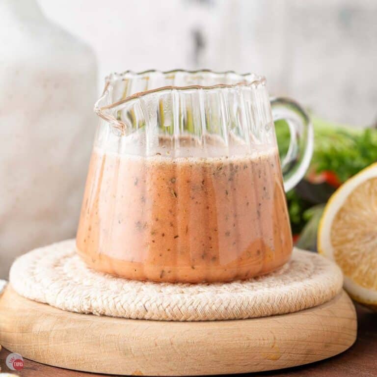 small jar with a handle full of red wine vinaigrette dressing sitting on a wood board