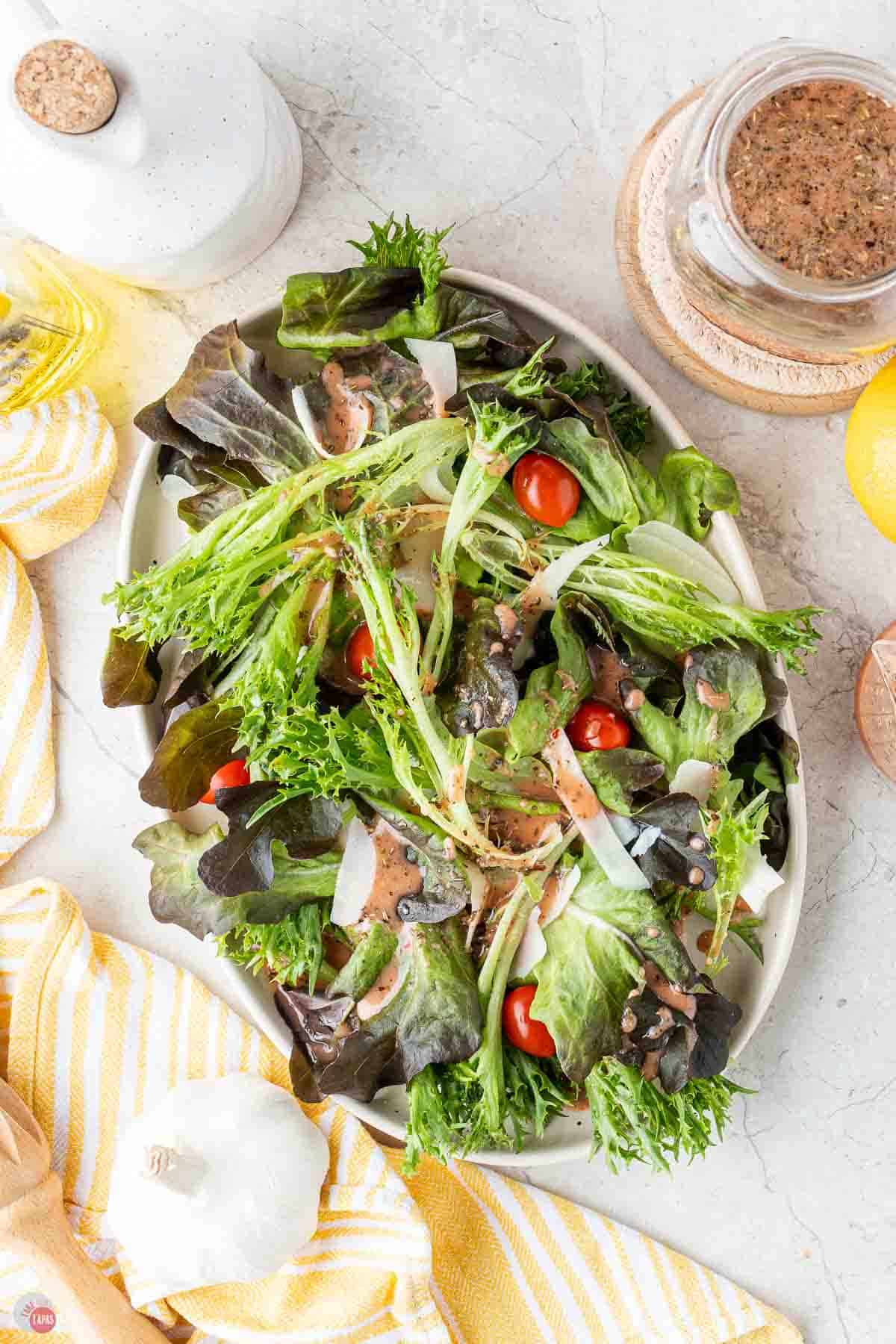 large salad on a silver bowl topped with vinaigrette dressing