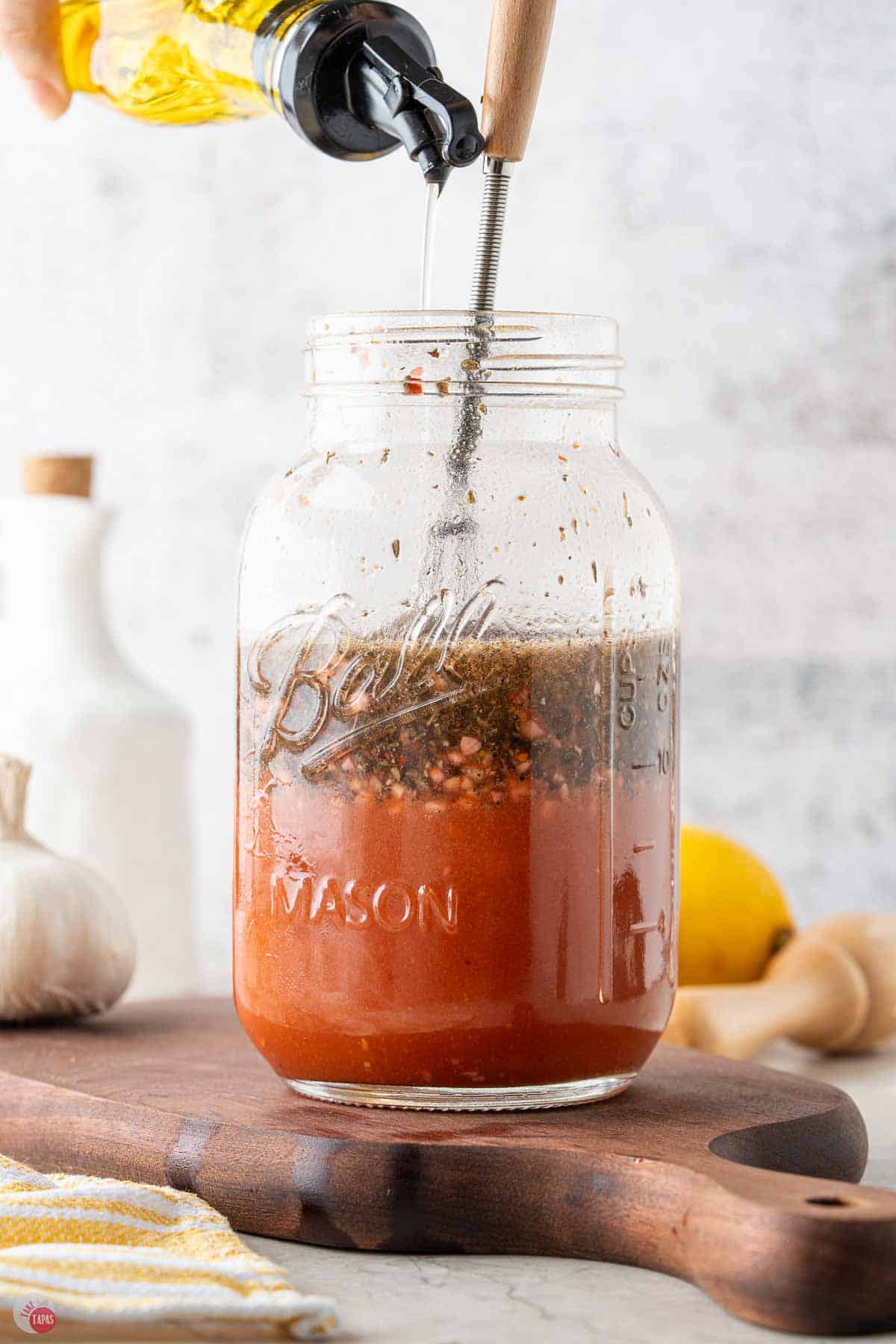 homemade salad dressing being whisked in a clear mason jar