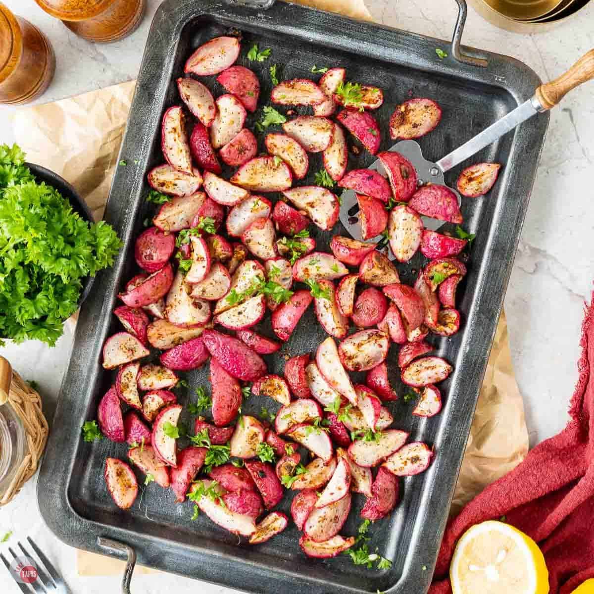 baking sheet topped with roasted radishes and a spatula