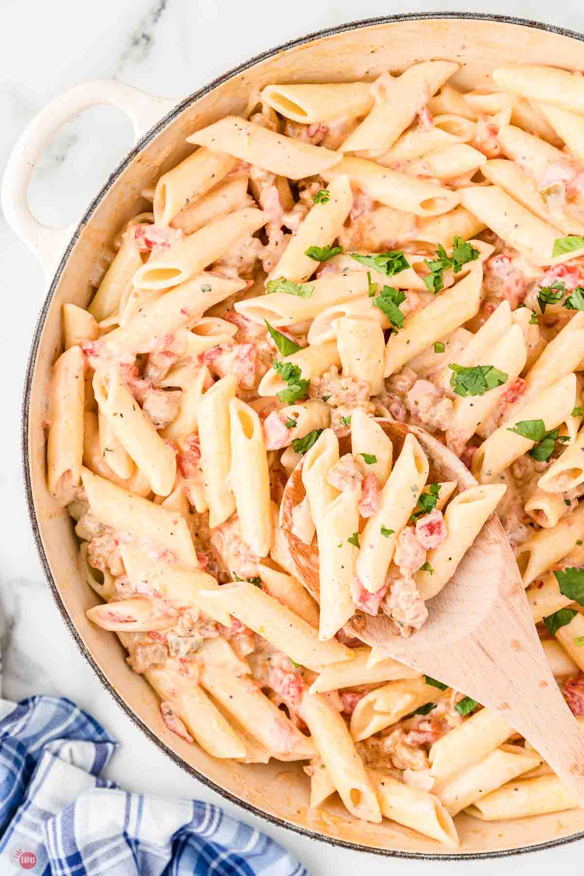 close up of skillet filled with penne pasta with a creamy rotel sauce
