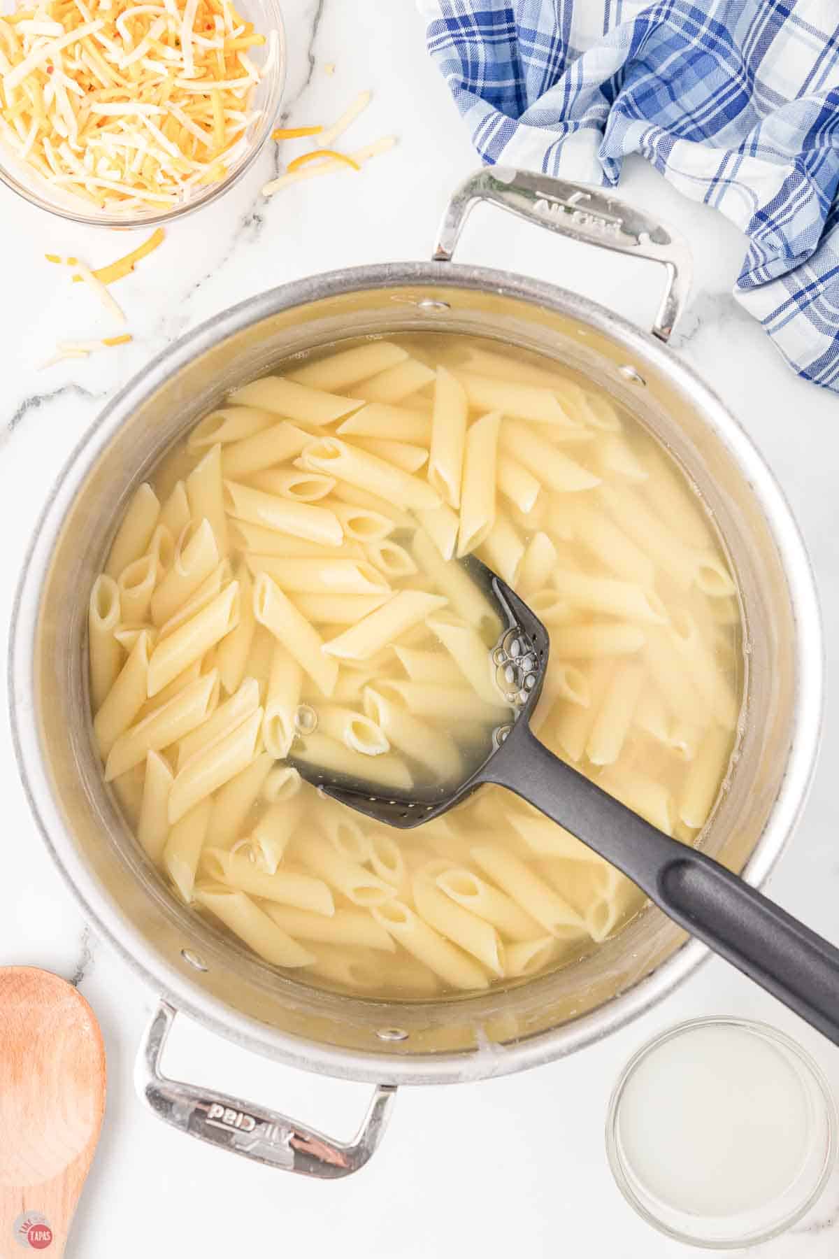 penne pasta cooking in a large silver pot
