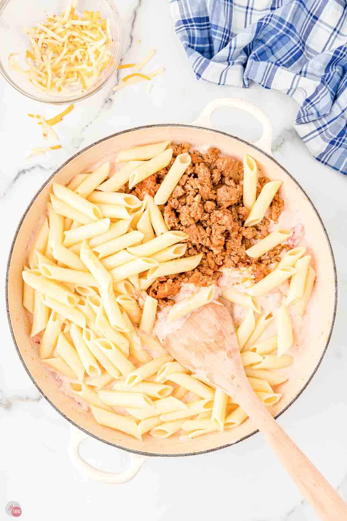 penne pasta in a skillet with cream sauce and sausage