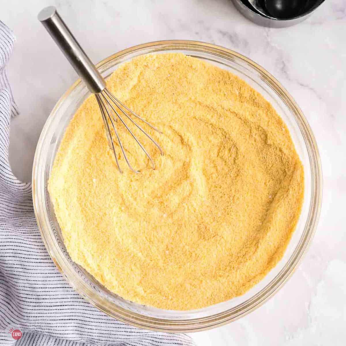 clear bowl of self-rising cornmeal mix being whisked