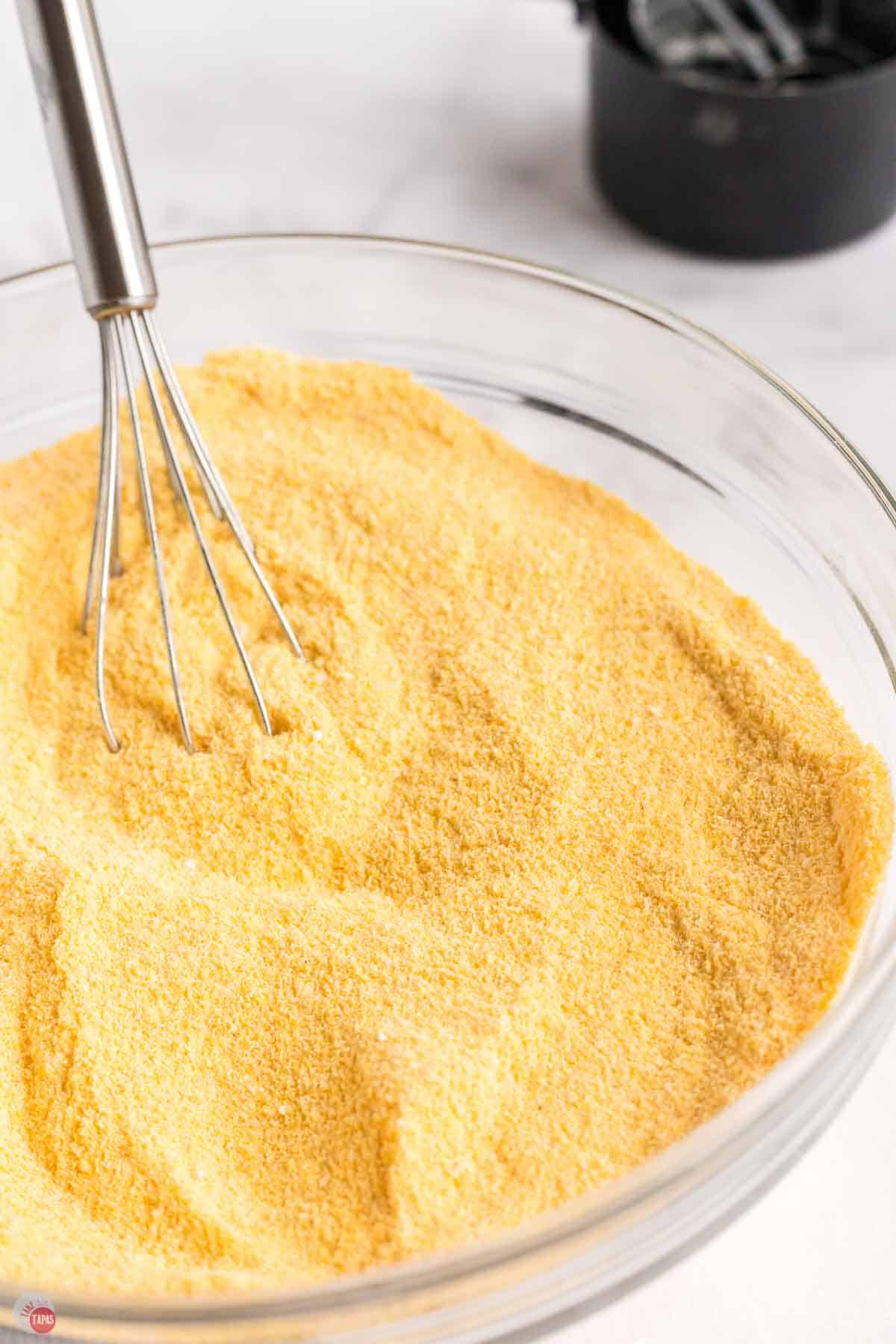 bowl of cornmeal mix being stirred with a whisk