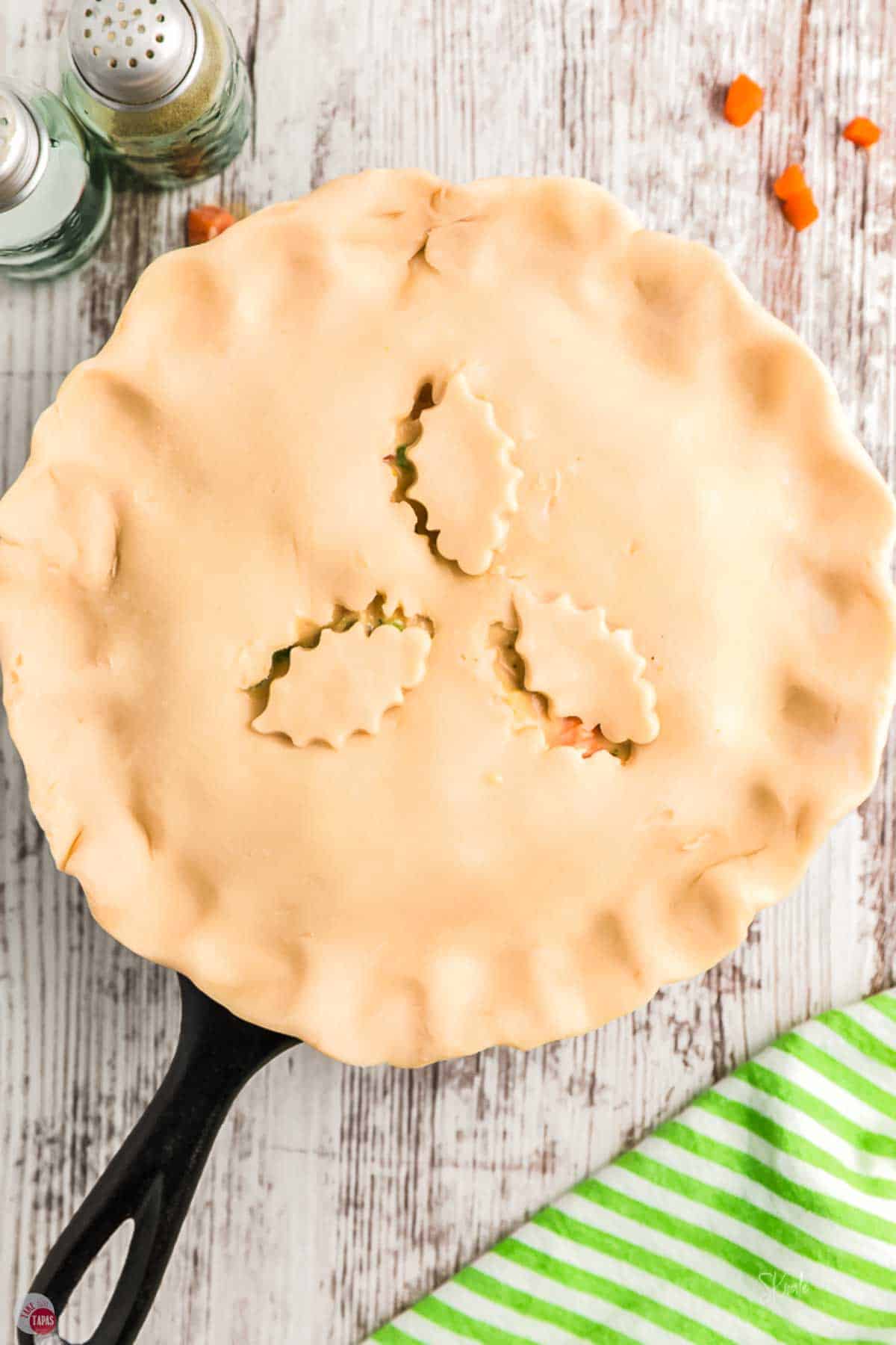 pie crust with decorative cut outs on top of a cast iron skillet