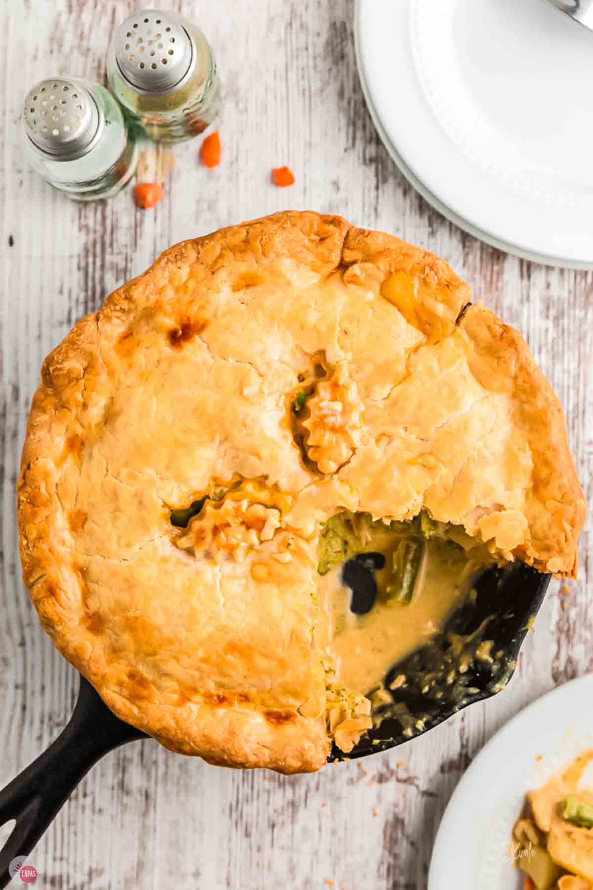 cast iron skillet with a chicken pot pie and a slice missing