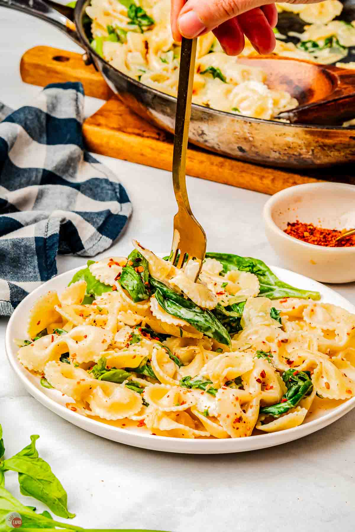 plate of pasta and spinach with a fork grabbing a bite