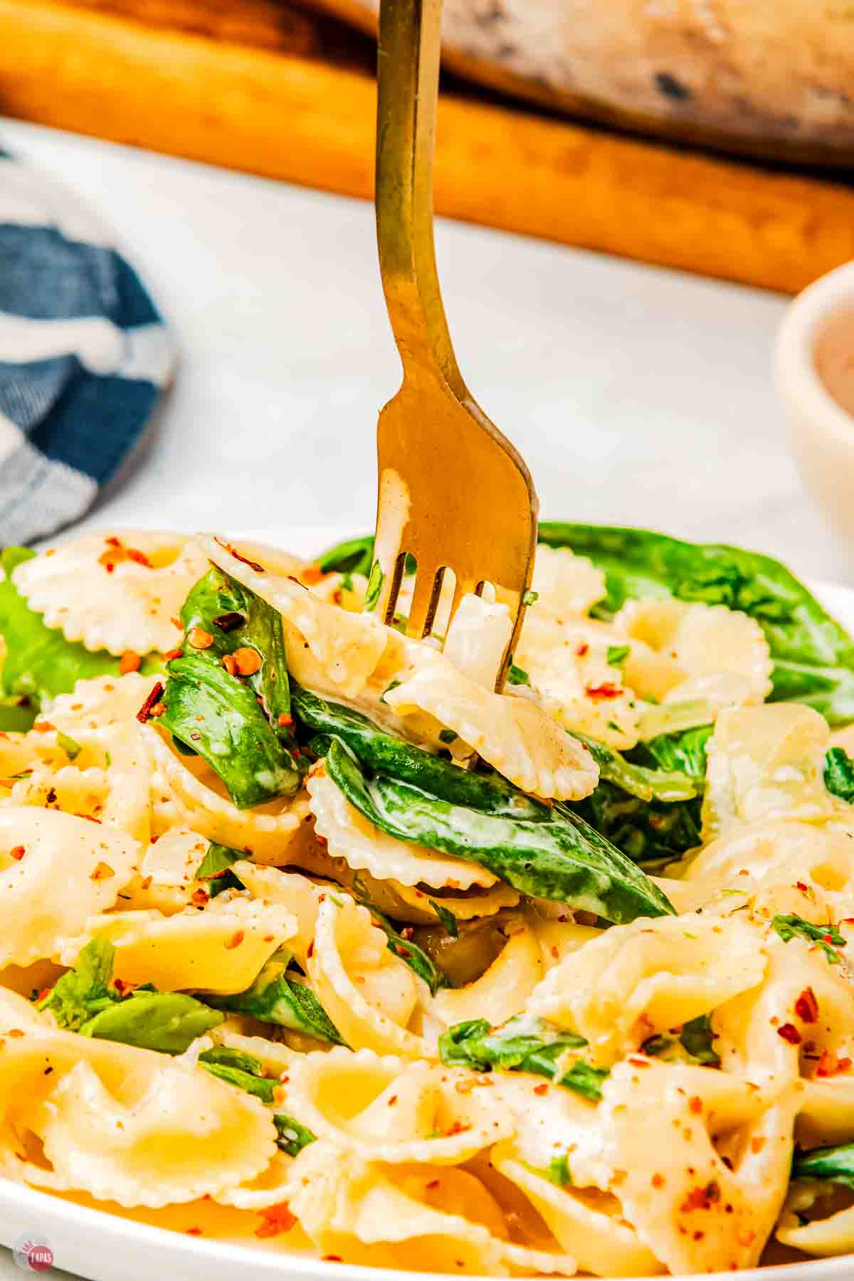 plate with a fork poking pasta and spinach