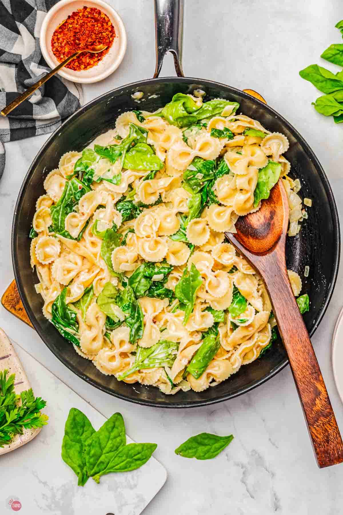 skillet with pasta and a sour cream spinach sauce