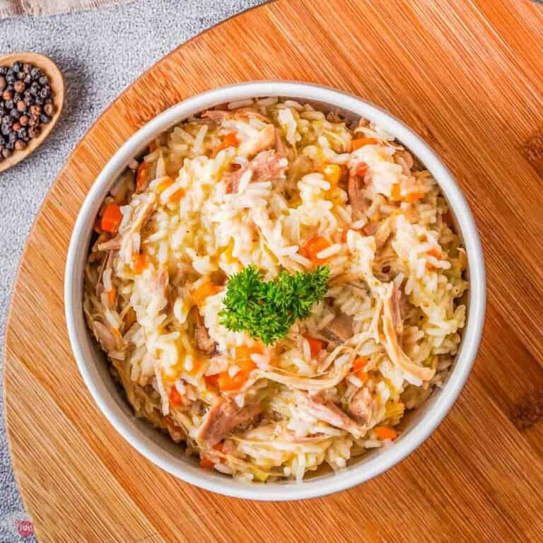 bowl of chicken and rice topped with parsley on a wood board