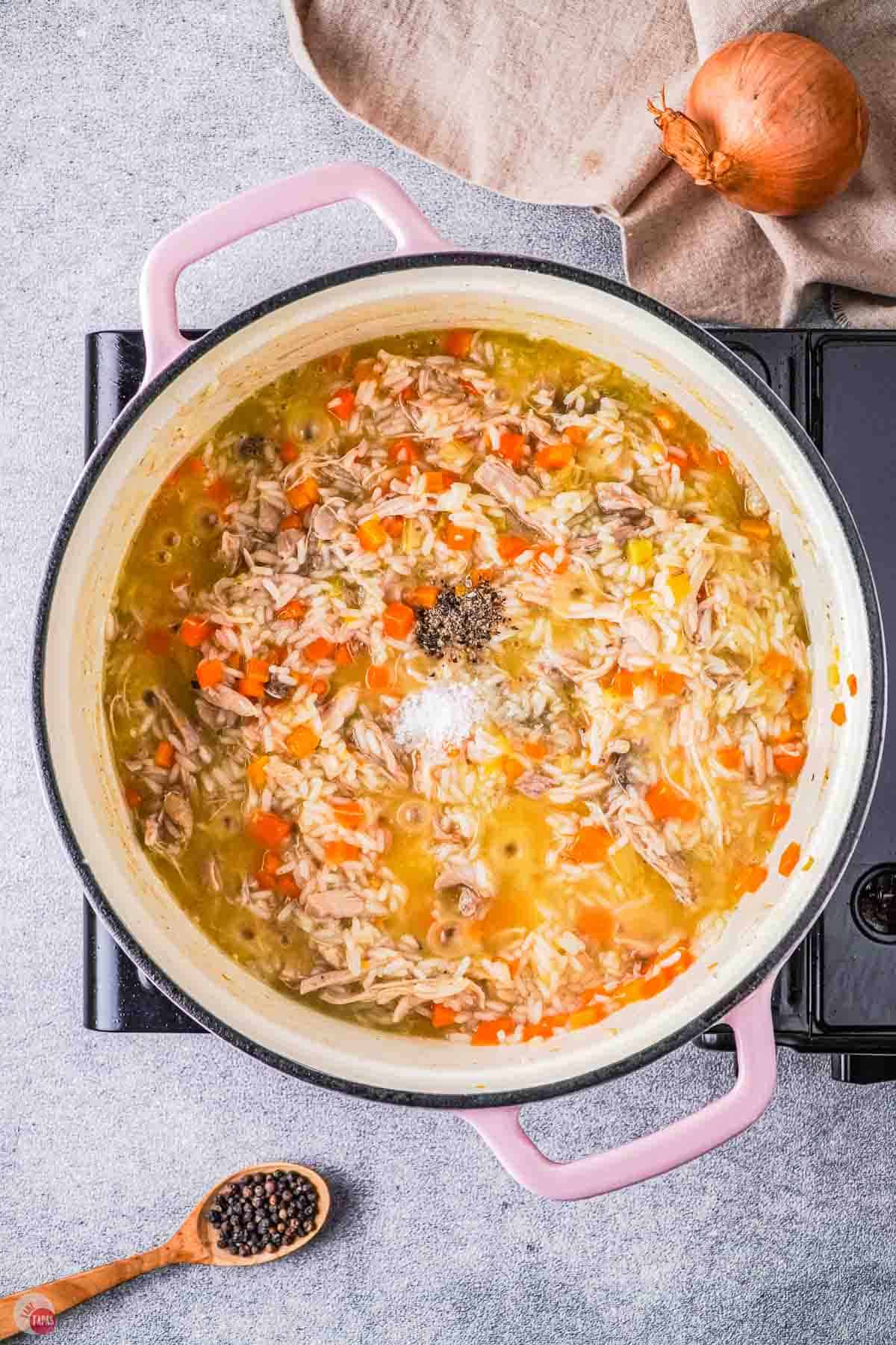 white pot of stewed chicken and rice topped with salt and pepper