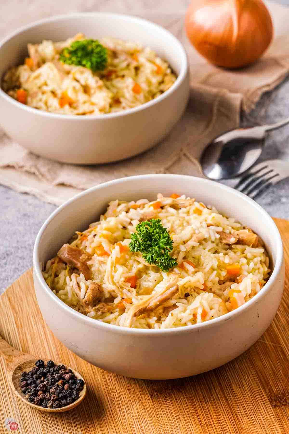 white bowl of stewed chicken and rice on a wood board