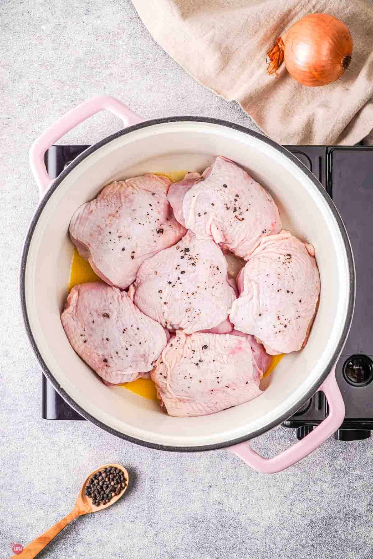 chicken thighs cooking in a white pot