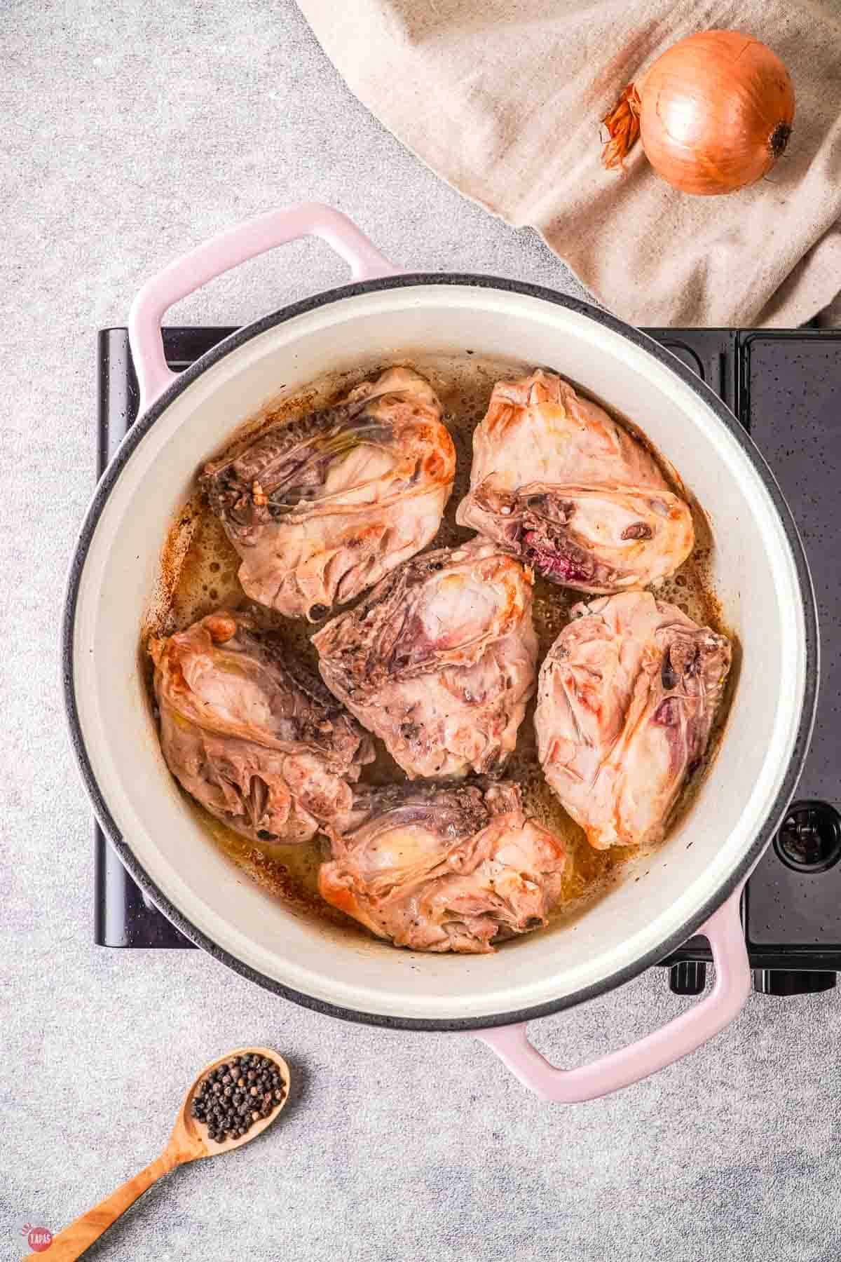 seared chicken thighs in a white pot