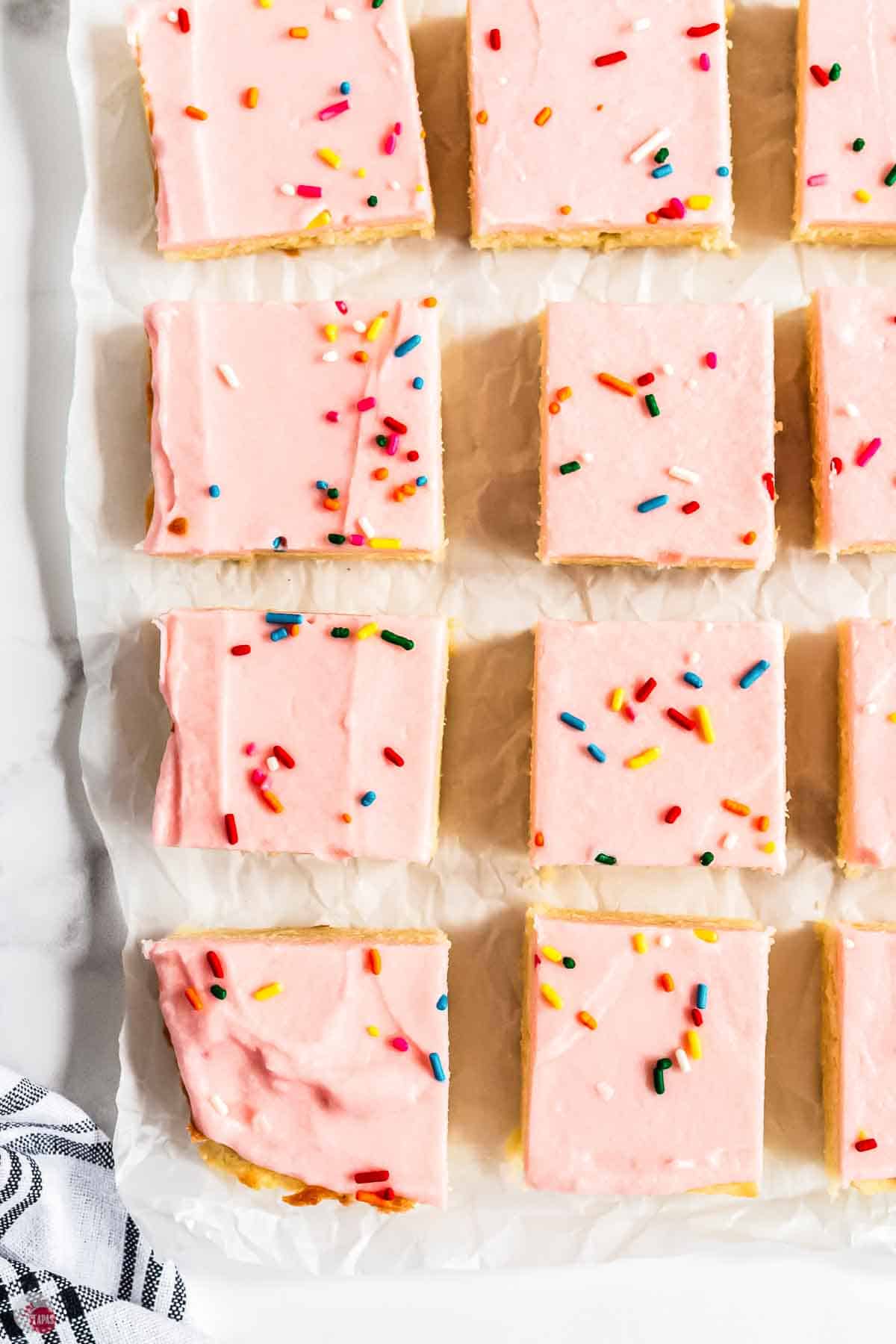 close up of sugar cookie bars with pink frosting and colored sprinkles