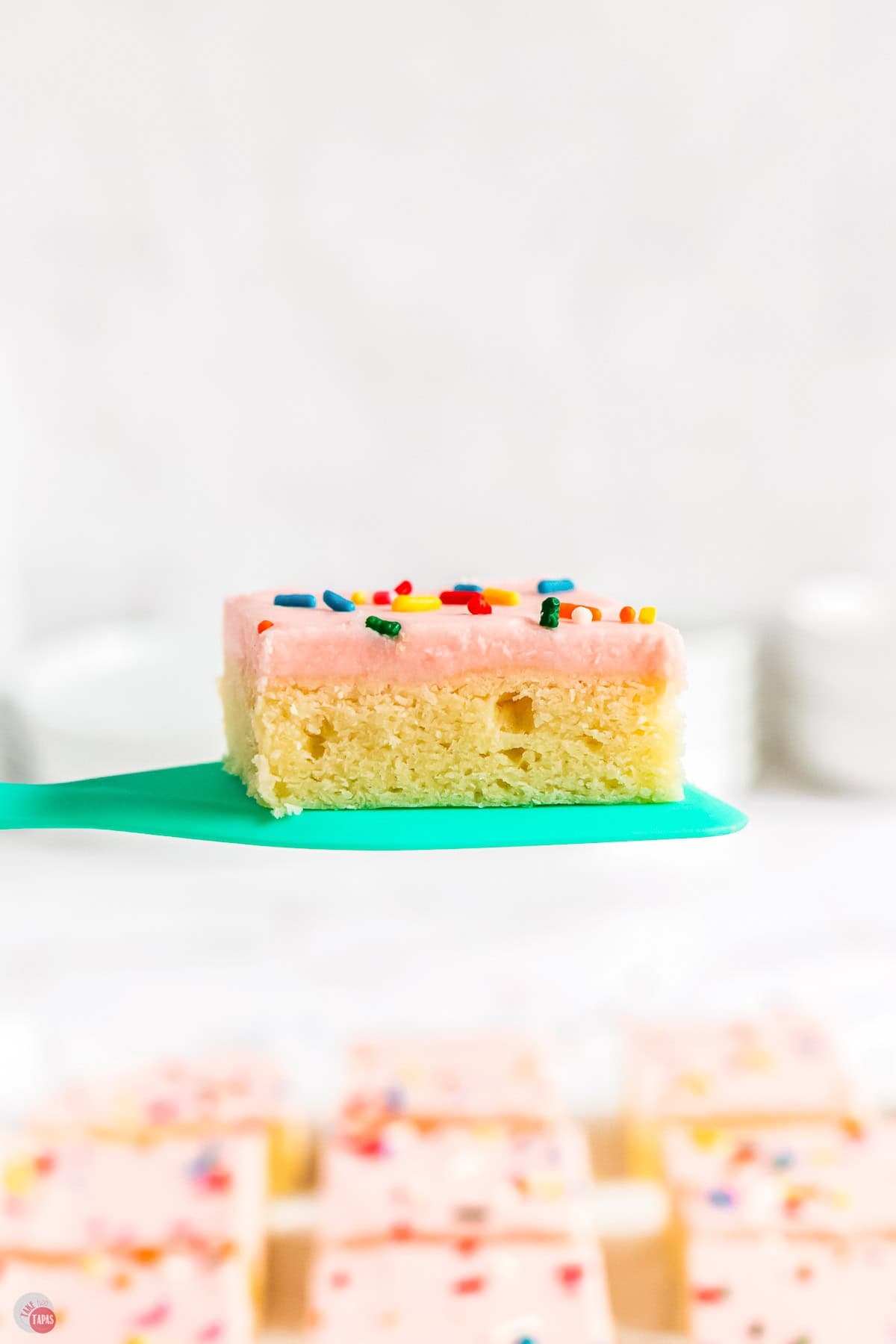 pink frosted sugar cookie bar on a green spatula