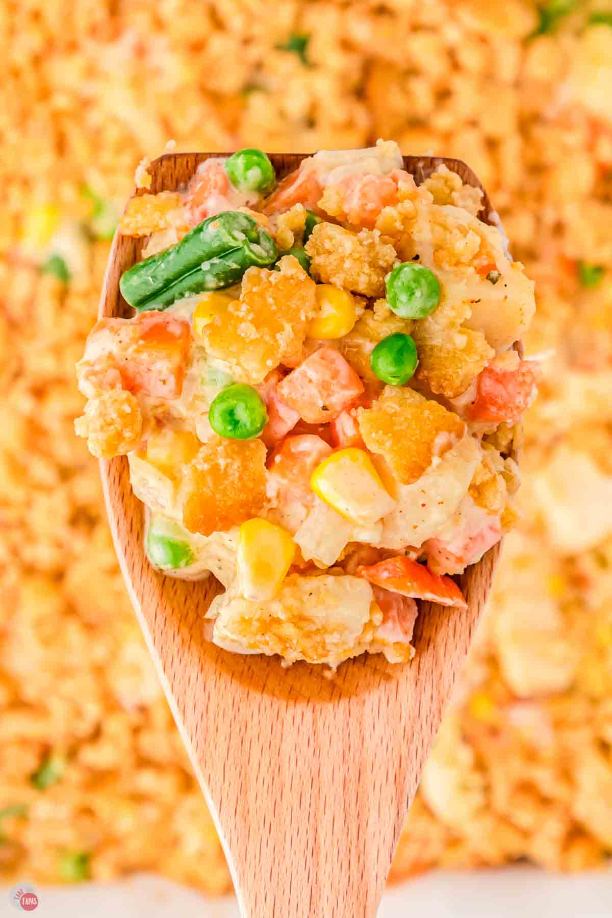 close up of scoop of veg all casserole on a wood spoon