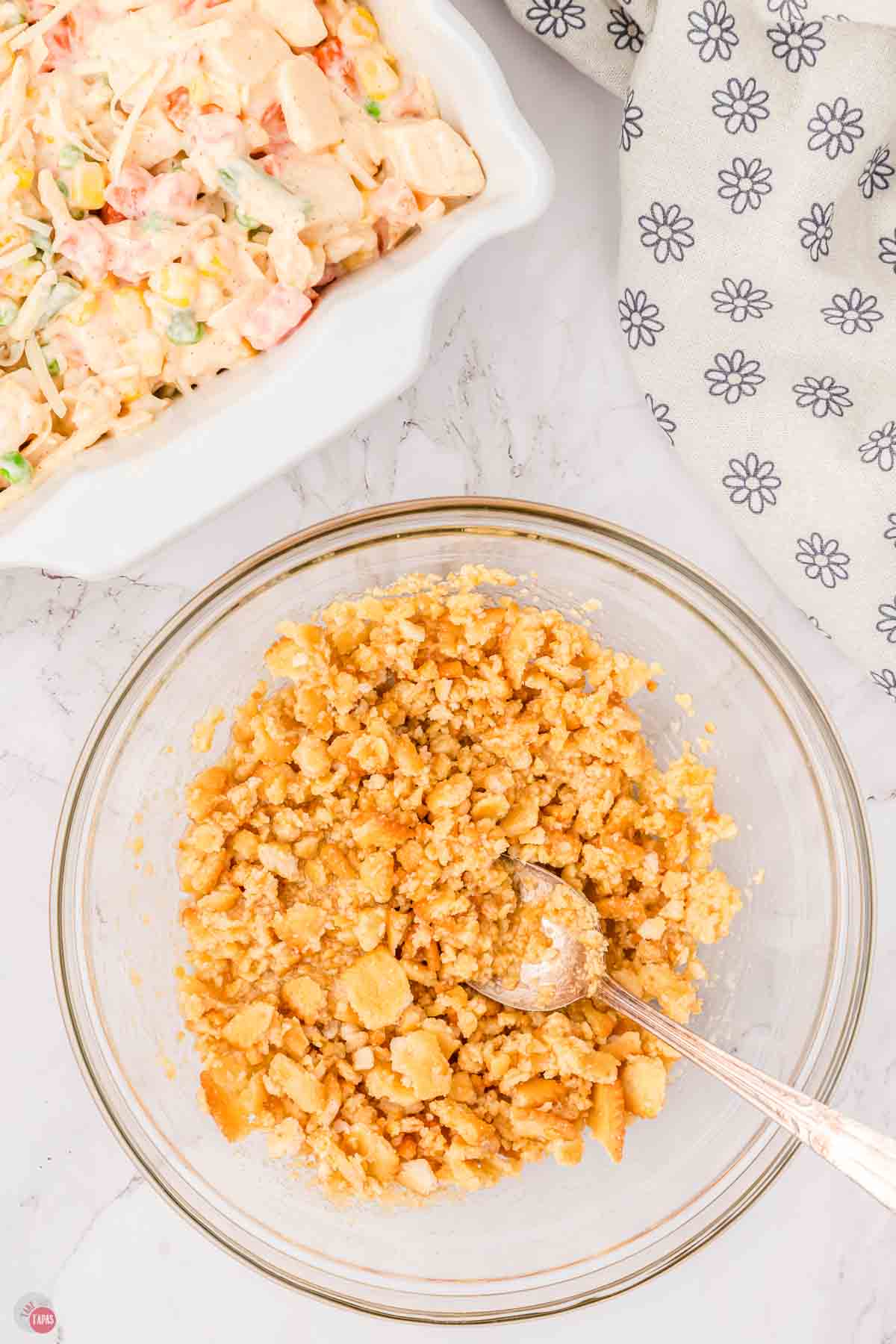 cracker crumbs being mixed with melted butter in a clear bowl