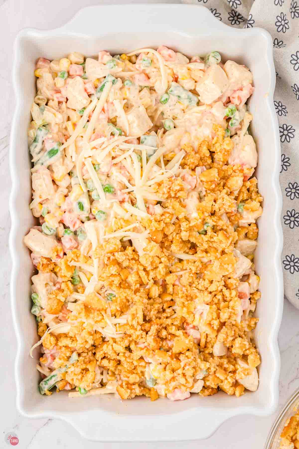 vegetable casserole in a white dish partially covered with cracker crumb topping