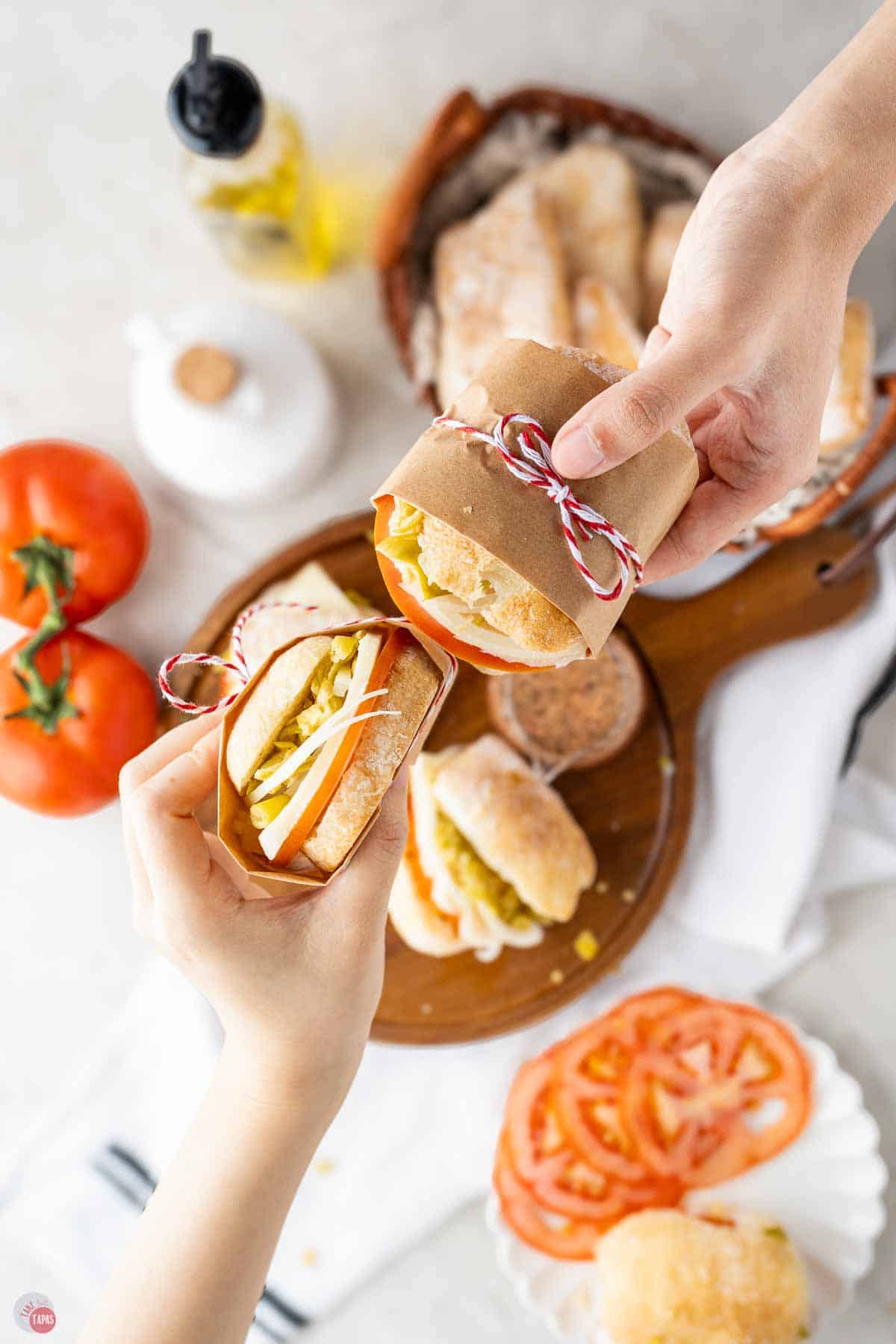 two hands holding sandwiches