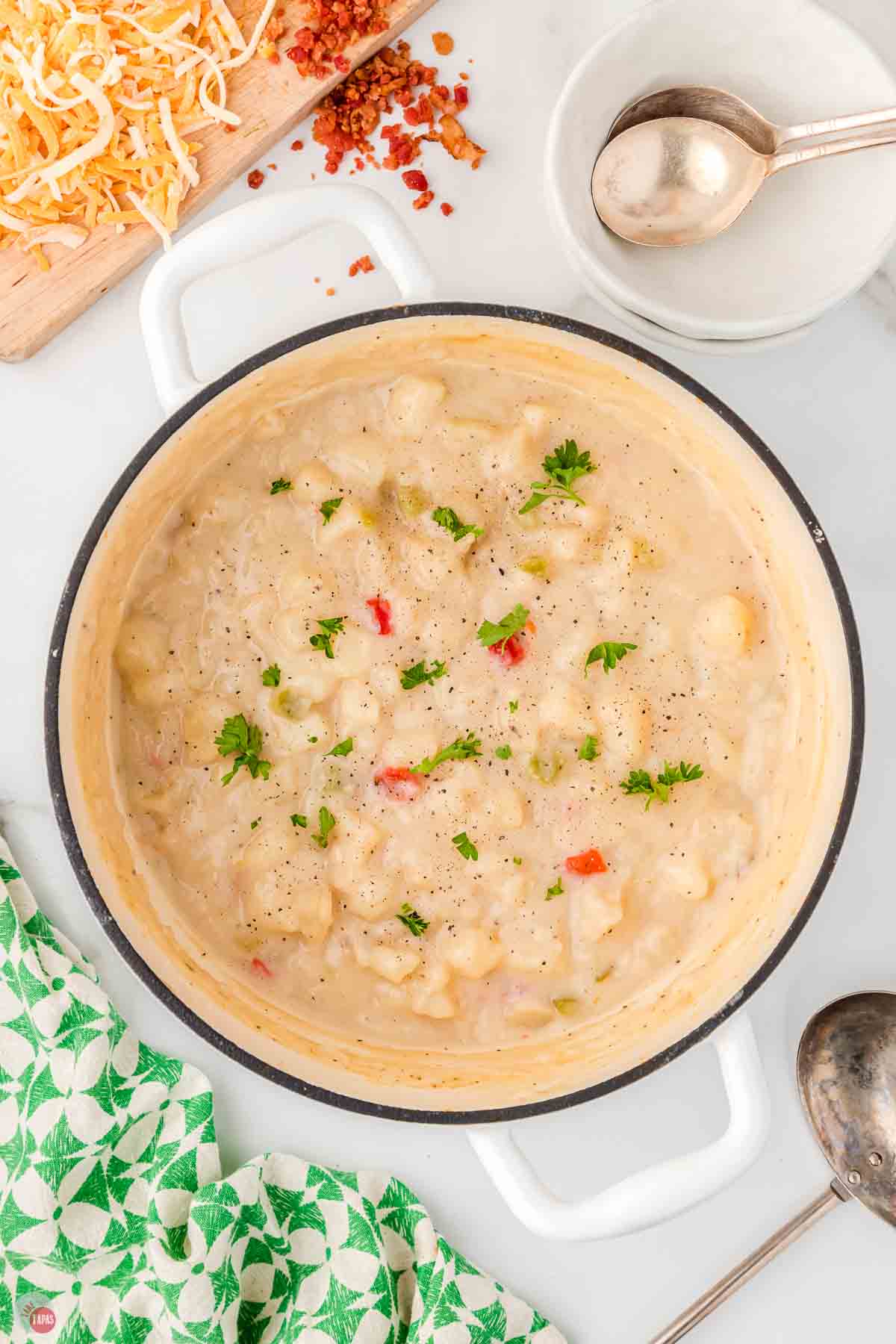 white pot full of potato soup topped with chopped parsley
