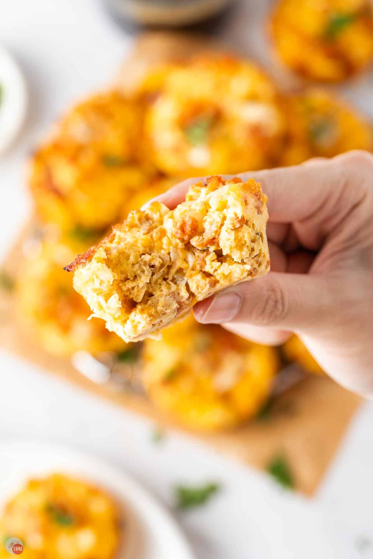 hand holding a breakfast casserole mini muffin with a bite taken out of it