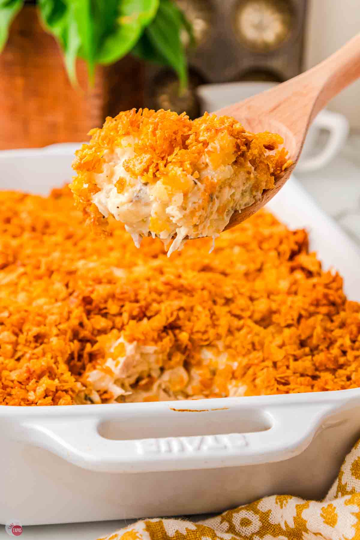 wood spoon scooping casserole out of a white dish