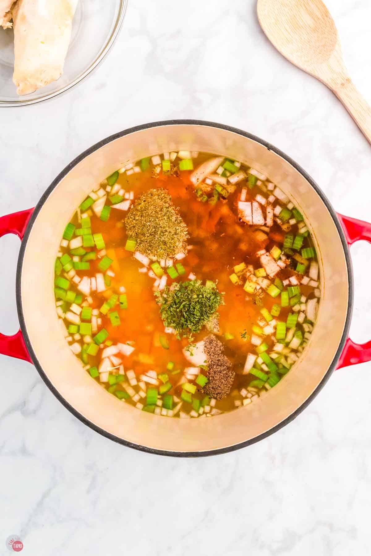 red pot with broth and diced vegetables