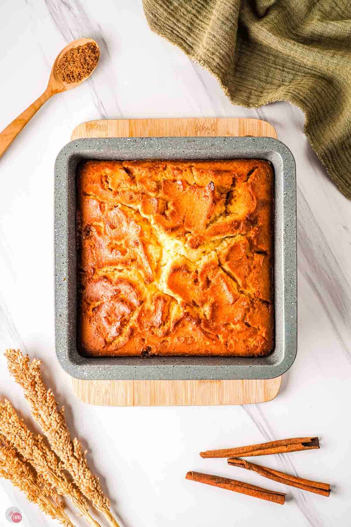 baked cake in a square pan on top of a wood board