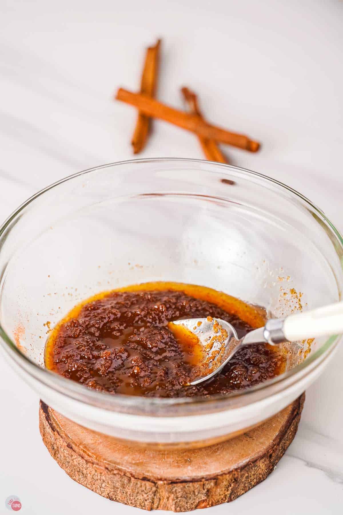clear mixing bowl with a cinnamon topping being mixed with a spoon