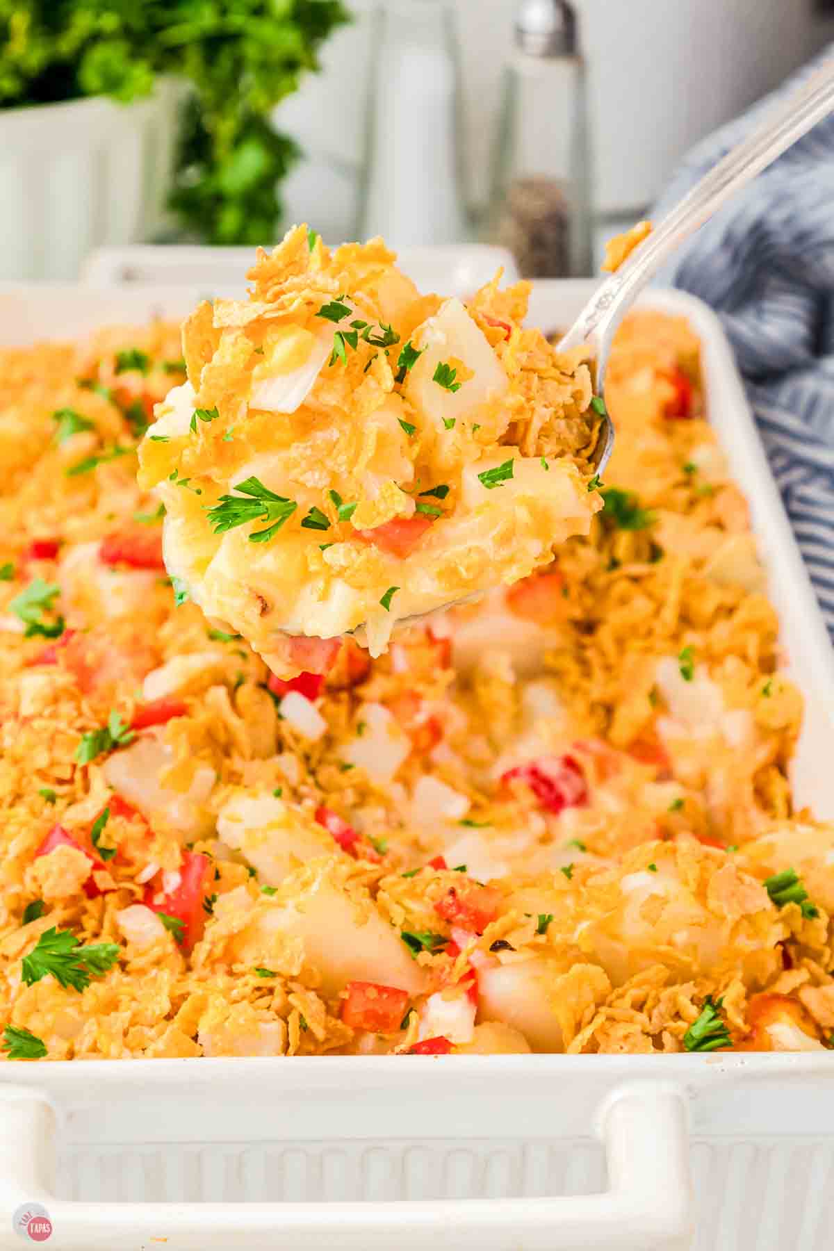 large spoon scooping potatoes out of a baking dish