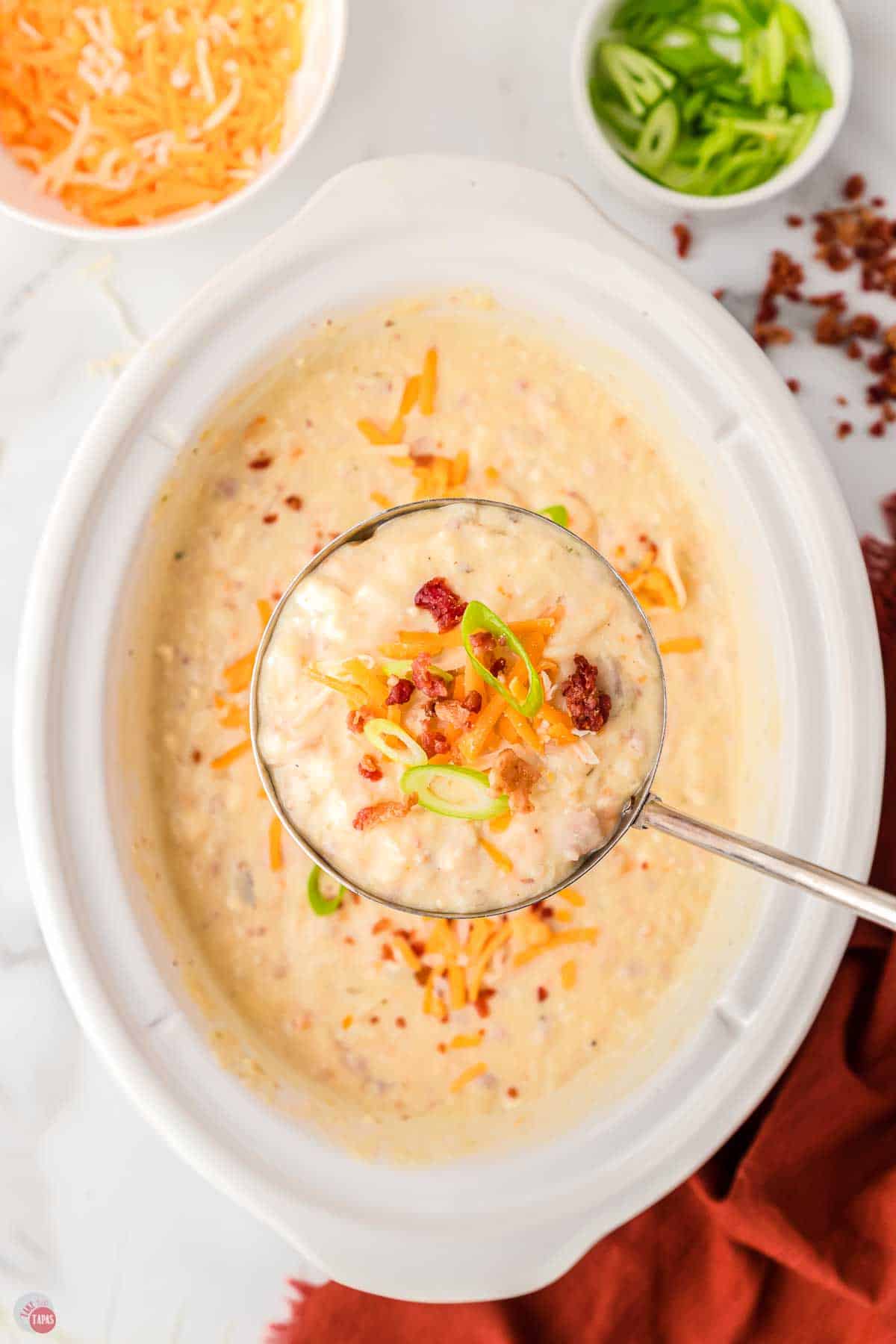 overhead view of potato soup in a crockpot with a ladle scooping some out