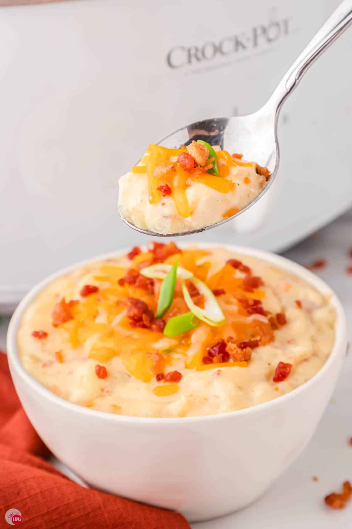 spoon with bite of soup topped with cheese and bacon