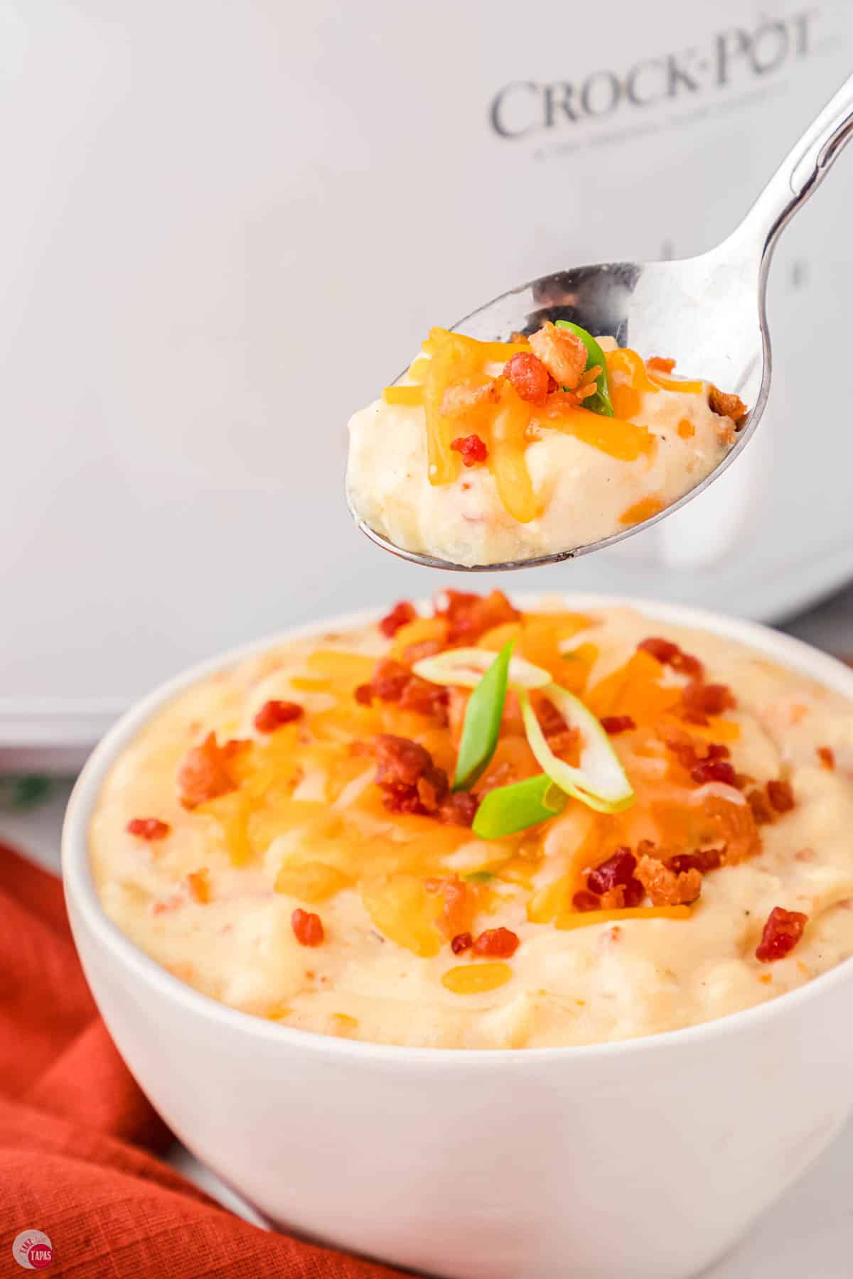 bowl of potato soup with a spoon scooping some out