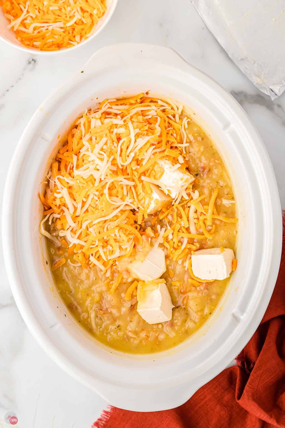 white crockpot filled with potatoes, cheese, and cream cheese