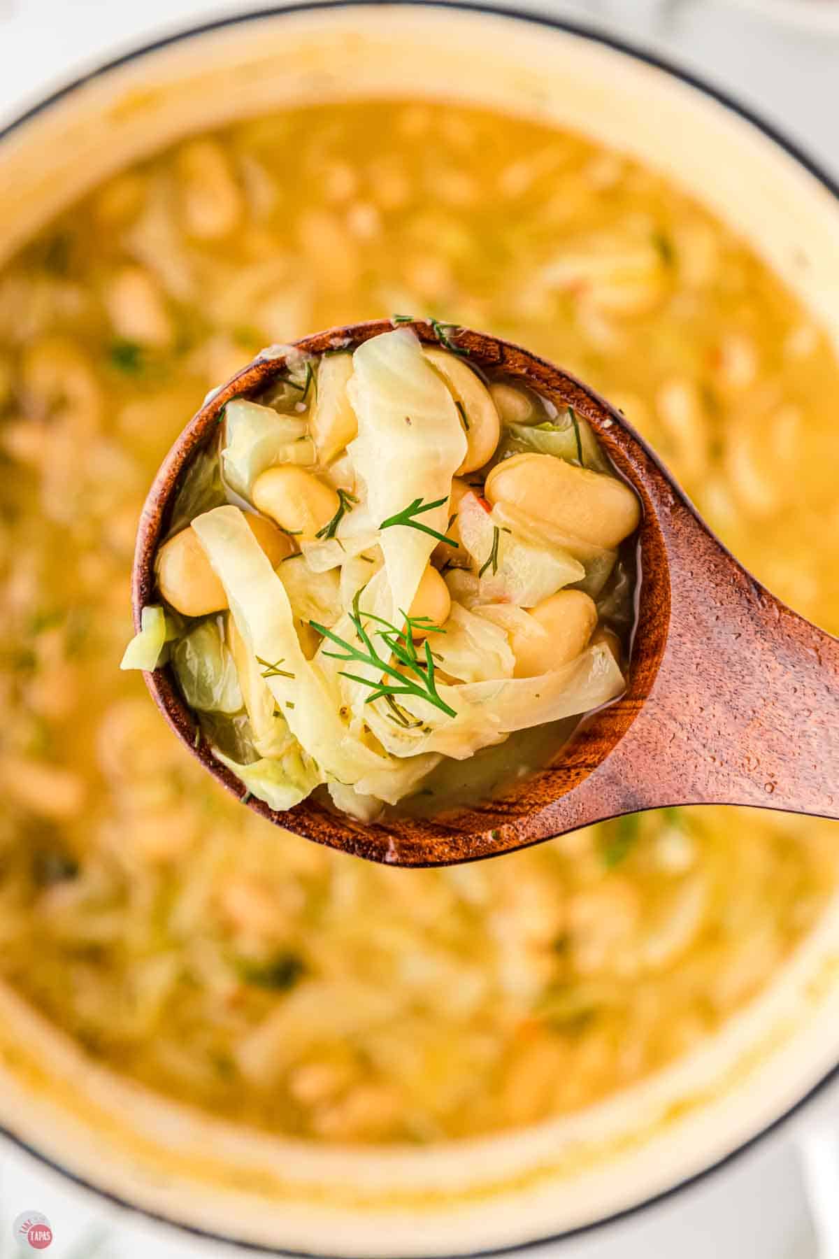 close up of wood spoon with bean soup in it