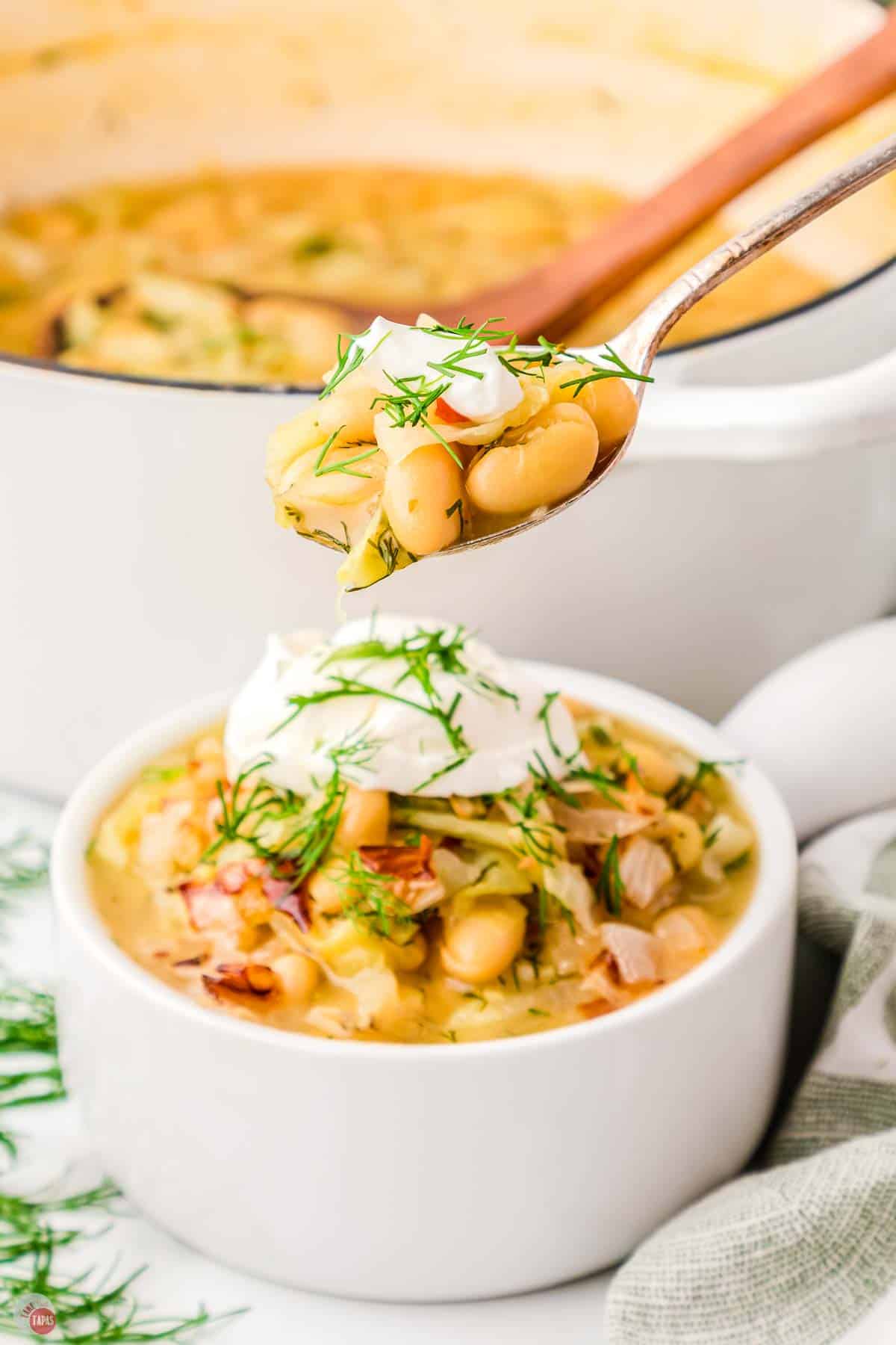 spoon with bite of soup over a small white bowl