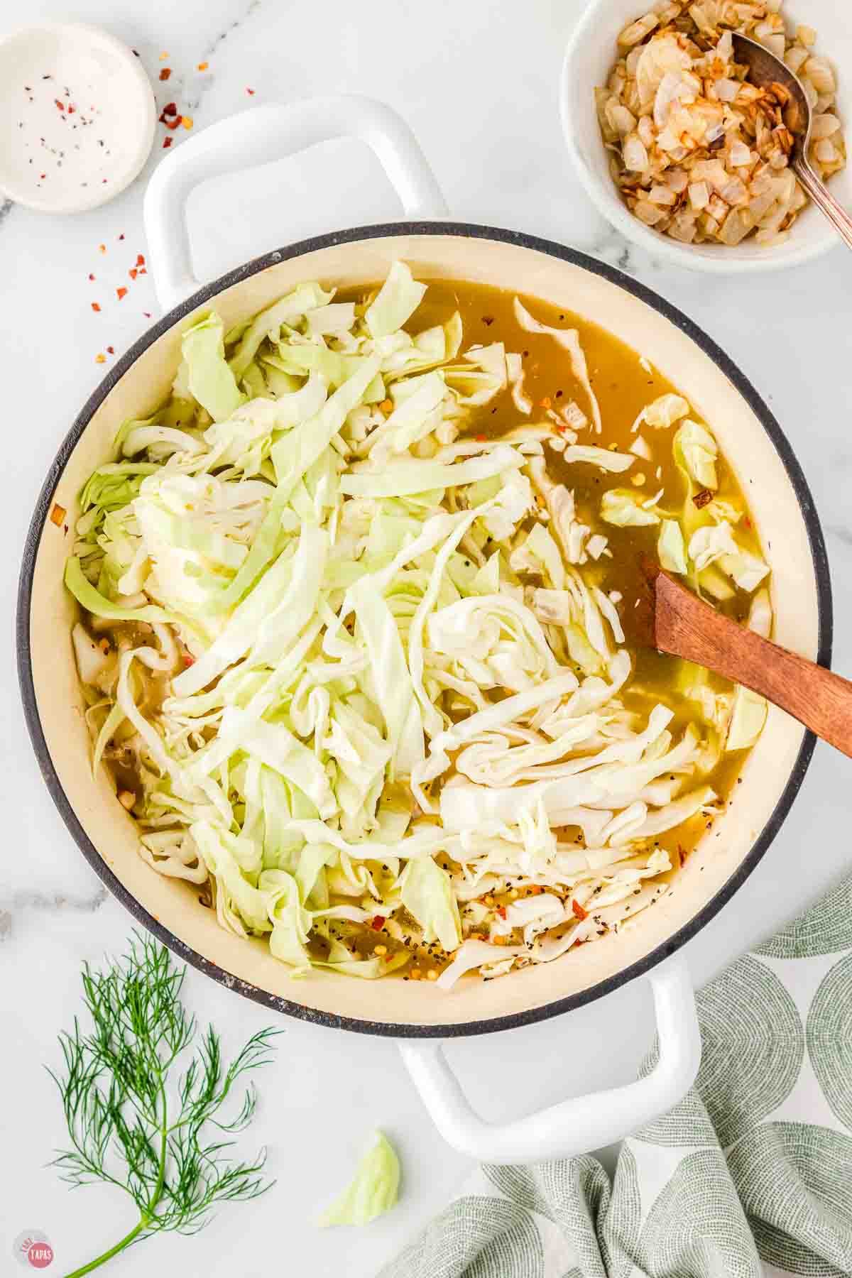 soup pot with broth and shredded cabbage being stirred in