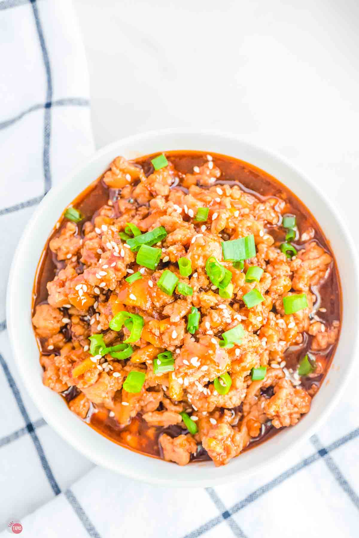 bowl of ground orange chicken topped with sliced green onions