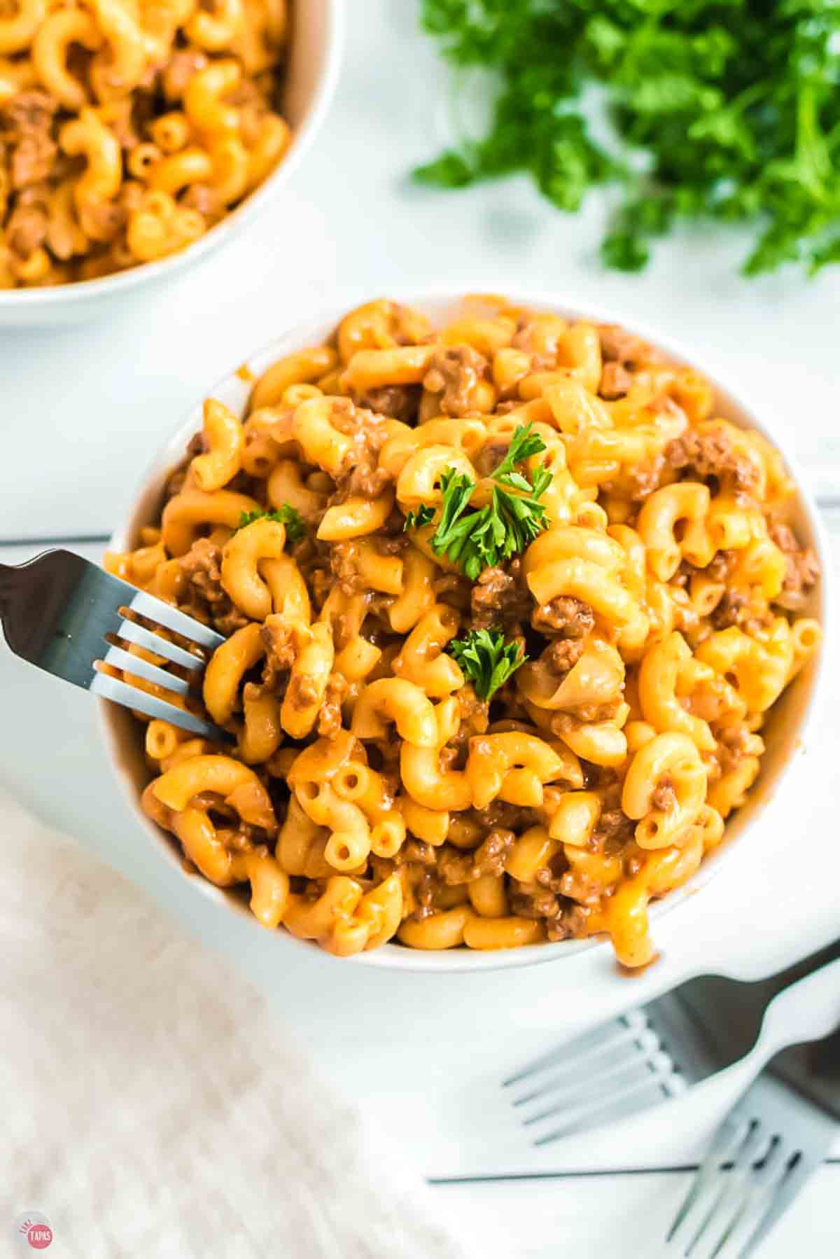 bowl of hamburger helper with a fork taking a bite out