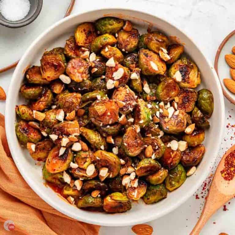 bowl of hot honey coated sprouts next to an orange napkin