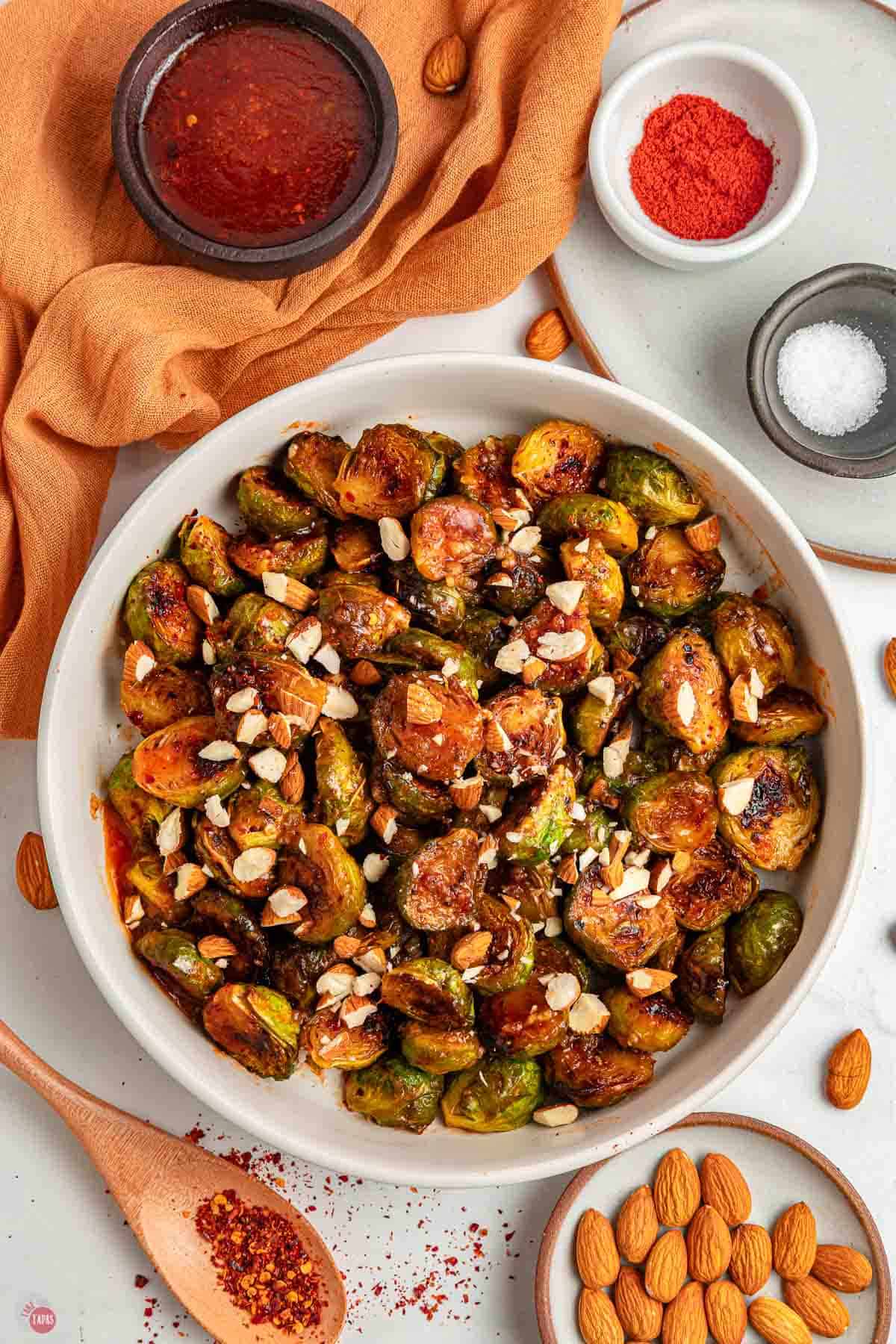 bowl of hot honey coated sprouts next to an orange napkin