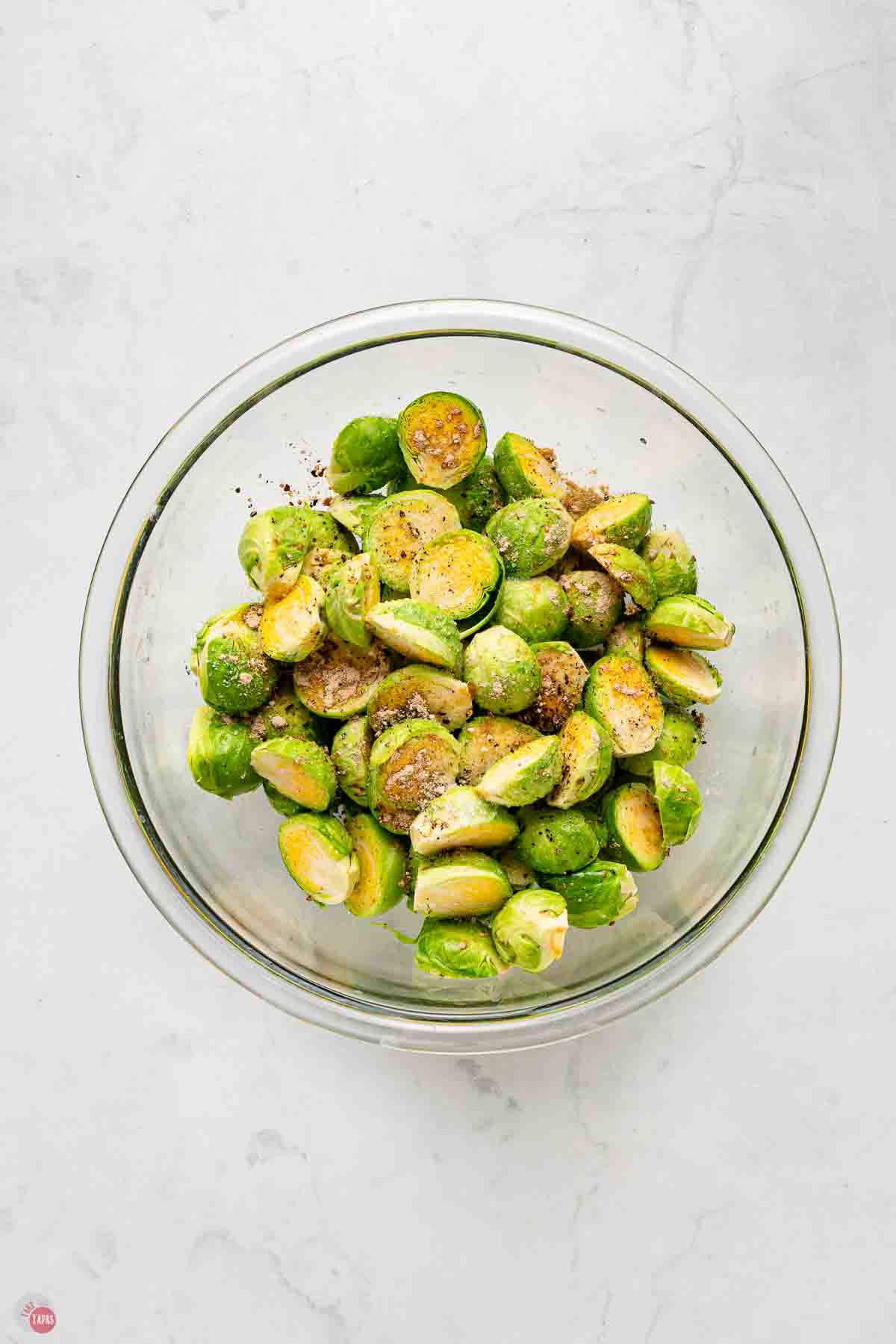 clear mixing bowl with trimmed and halved sprouts