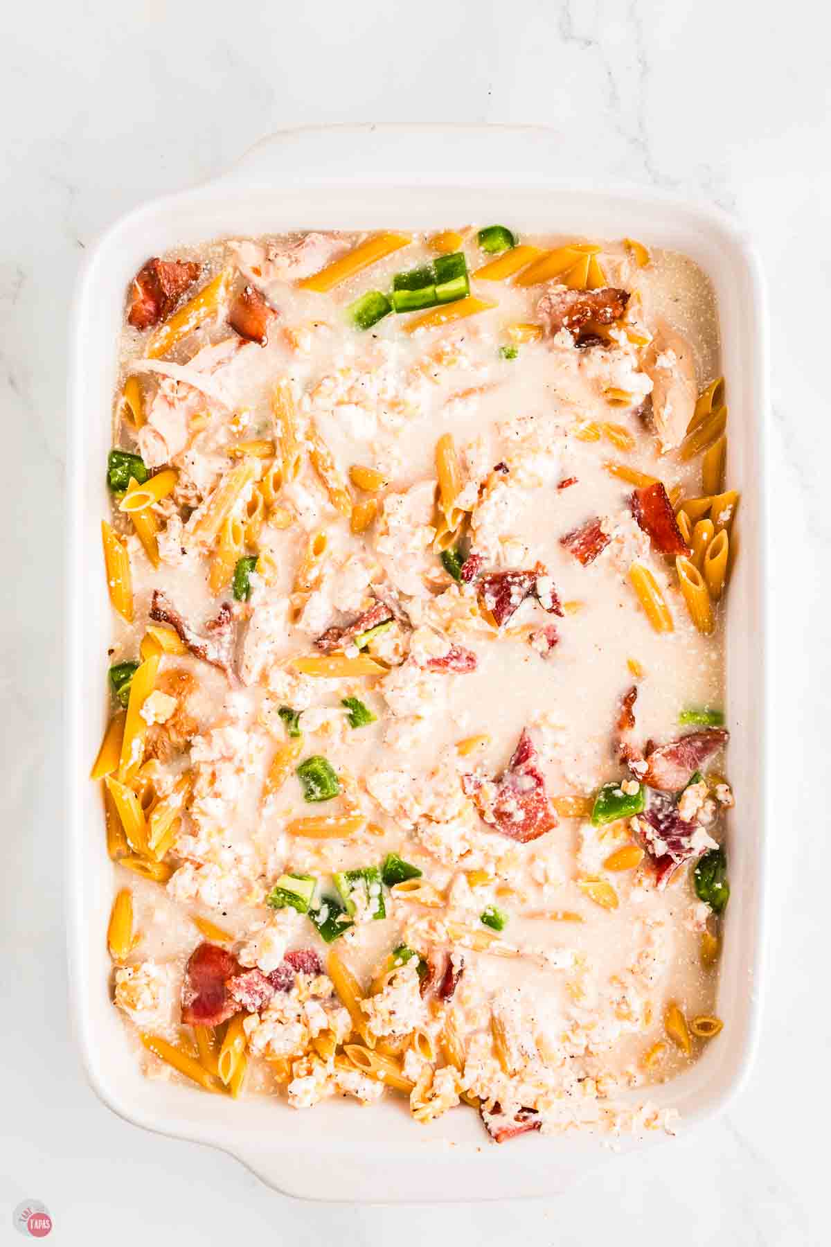 milk and cheese mixture in a baking dish with pasta noodles