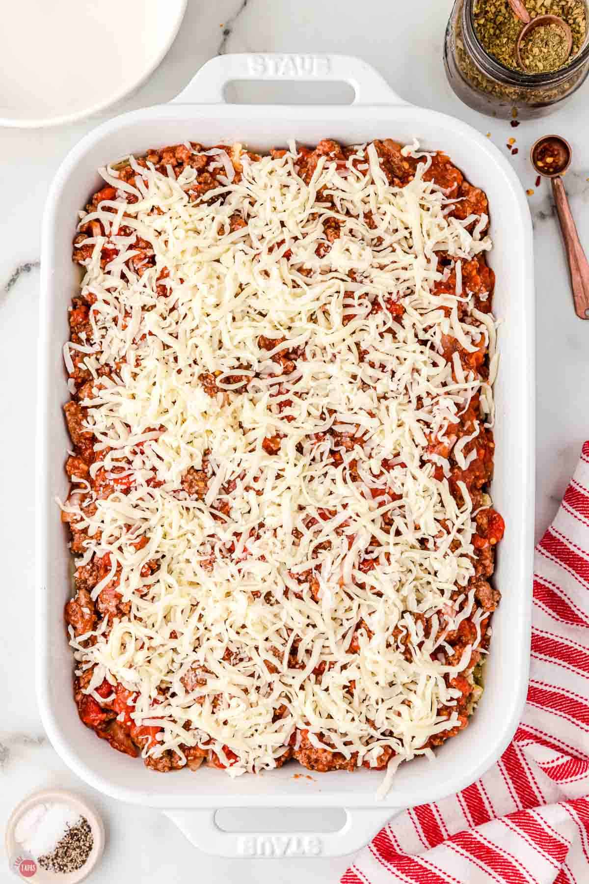 unbaked lasagna casserole topped with shredded cheese