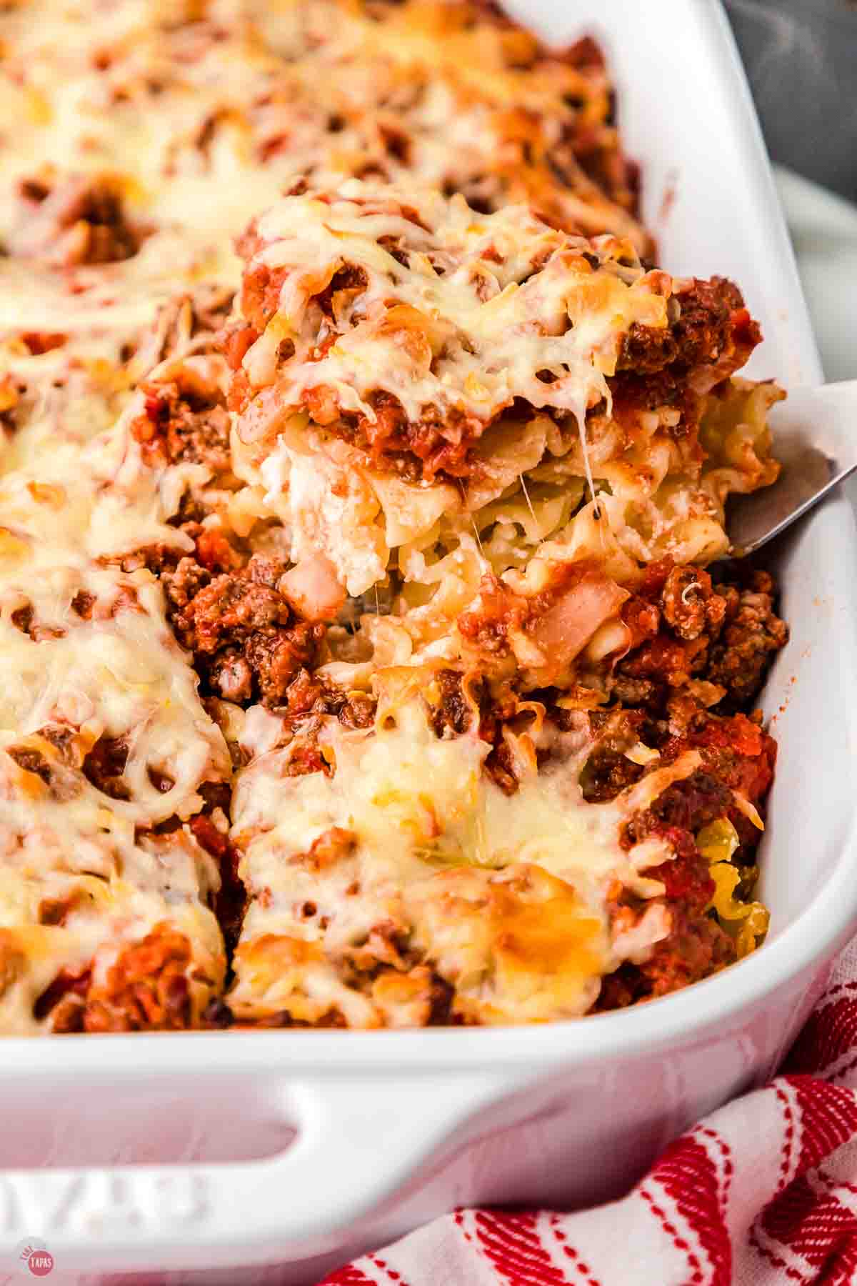 scoop of pasta casserole on a metal spatula over a dish