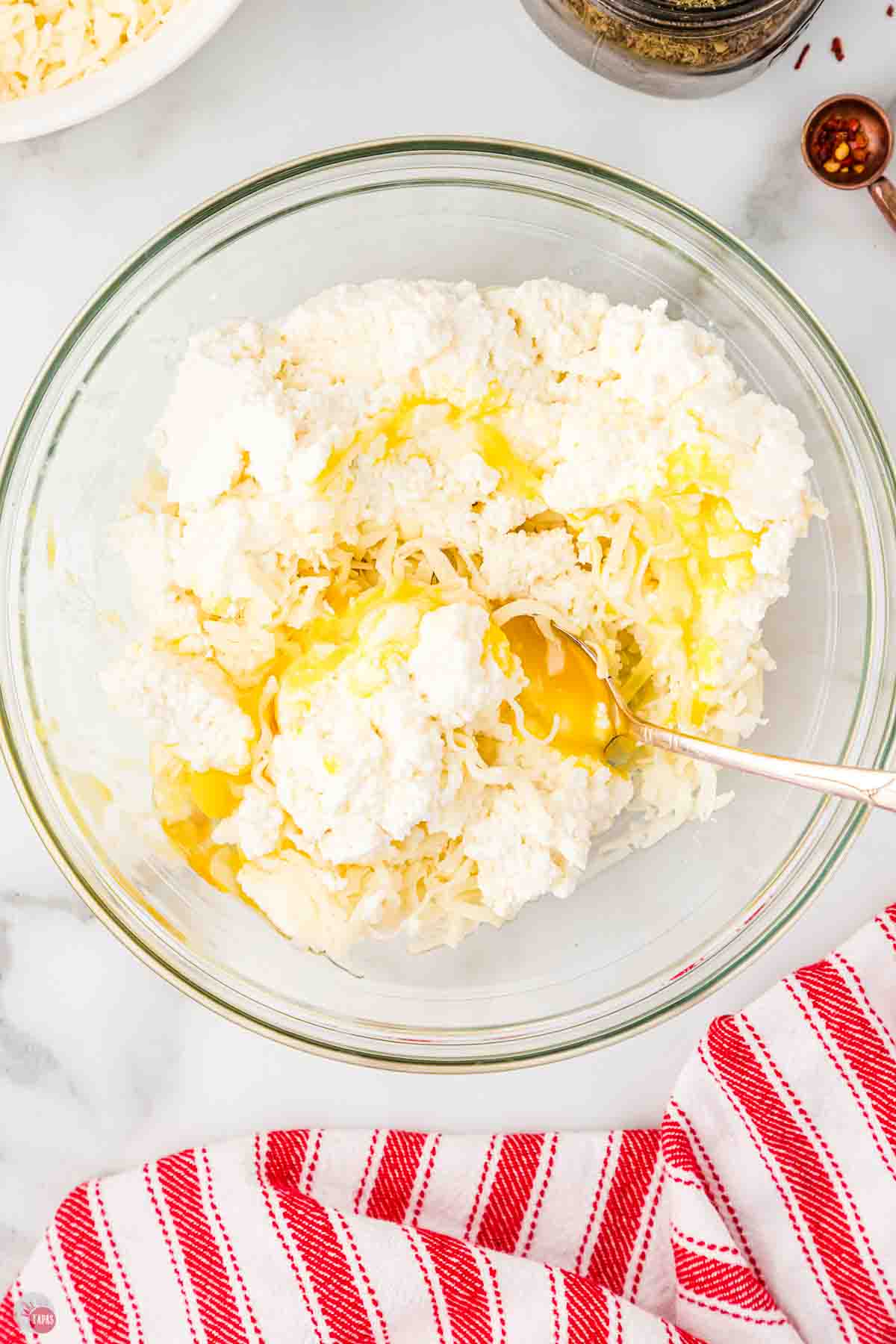 clear mixing bowl with ricotta cheese, eggs, and parmesan cheese